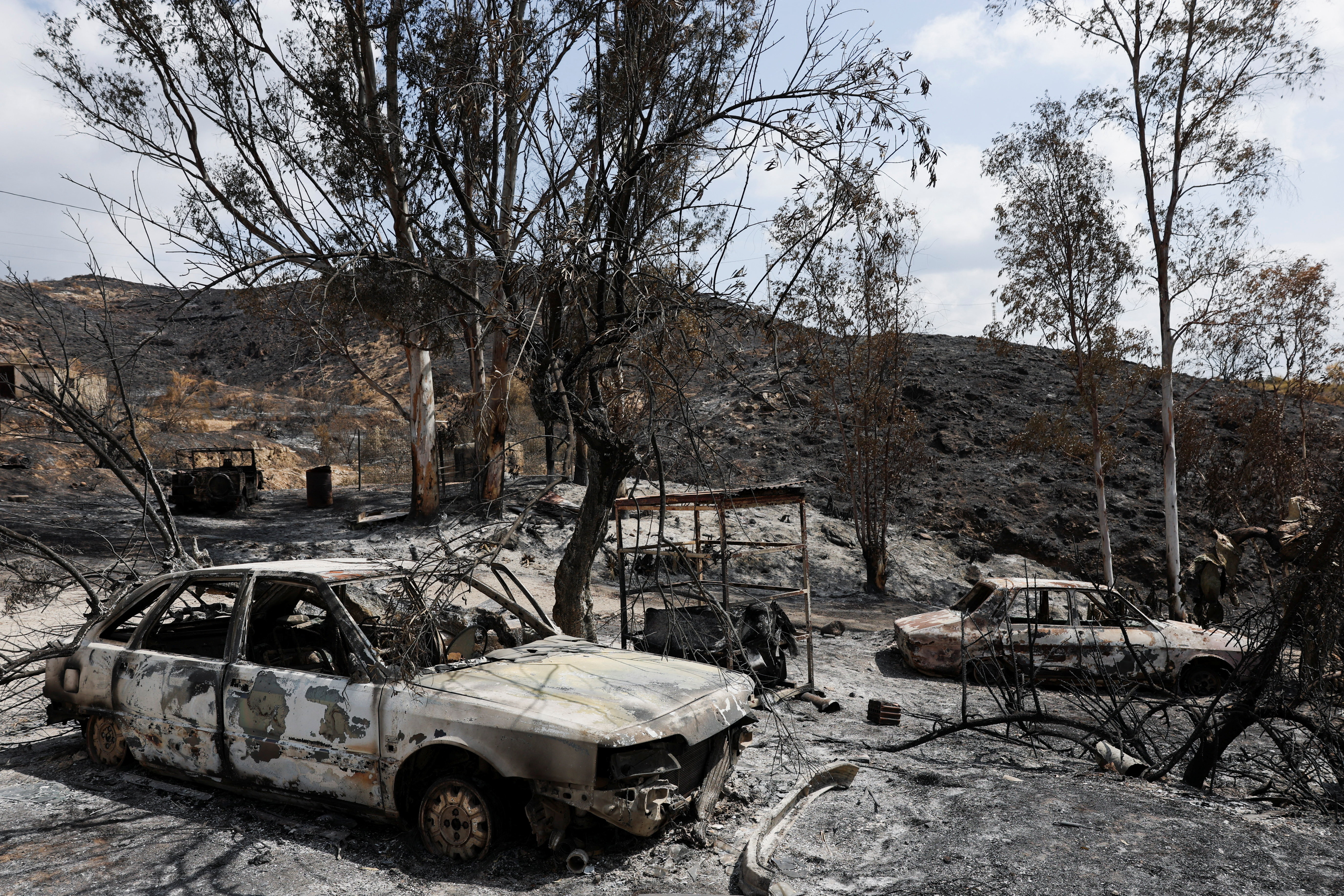 A charred, parked car remains in a burned area in the proximity where authorities believe deadly wildfires affecting Almeria province started, in Almocaizar, Almeria, Spain, July 12, 2026. REUTERS/Violeta Santos Moura