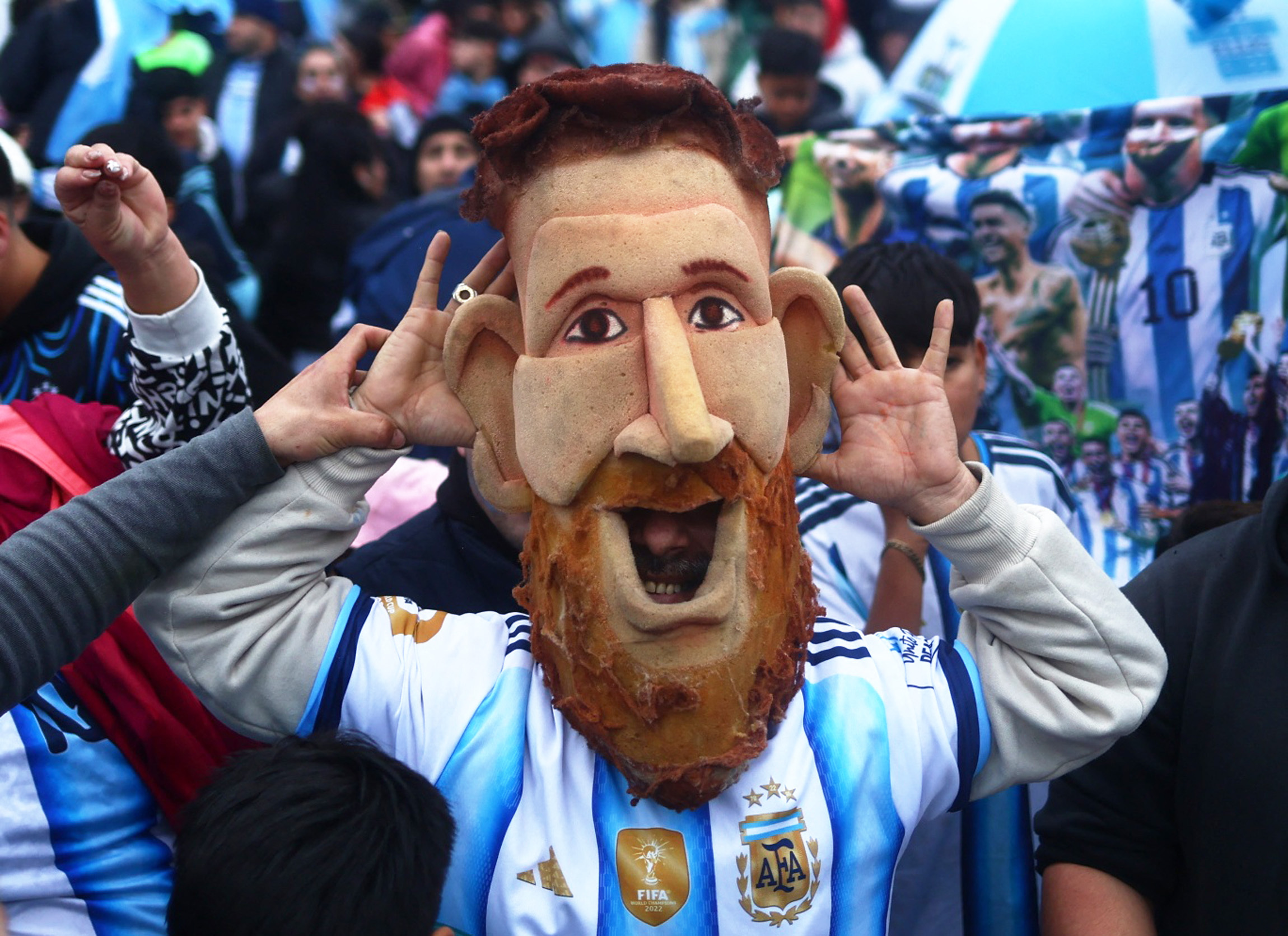 Soccer Football - FIFA World Cup 2026 - Argentina players arrive in Buenos Aires after the final - Buenos Aires, Argentina - July 20, 2026 Argentina fan wearing a Lionel Messi mask gestures as supporters gather outside the Argentine Football Association (