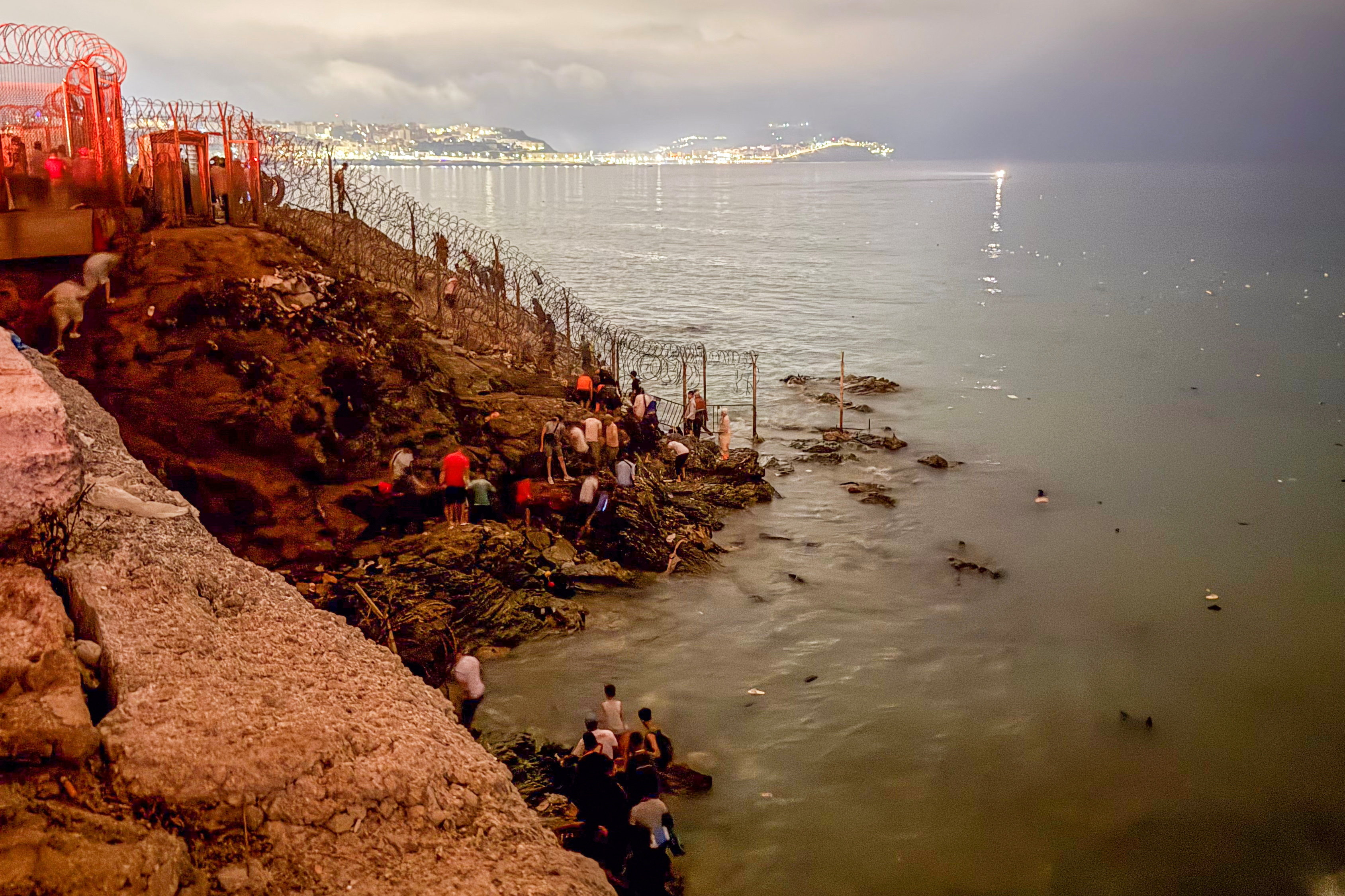 Migrants gather near a fence while waiting for a chance to cross to the Spanish enclave of Ceuta, on the Moroccan side of the border in Fnideq, Morocco, July 31, 2026. Picture taken with a mobile phone. REUTERS/Stringer