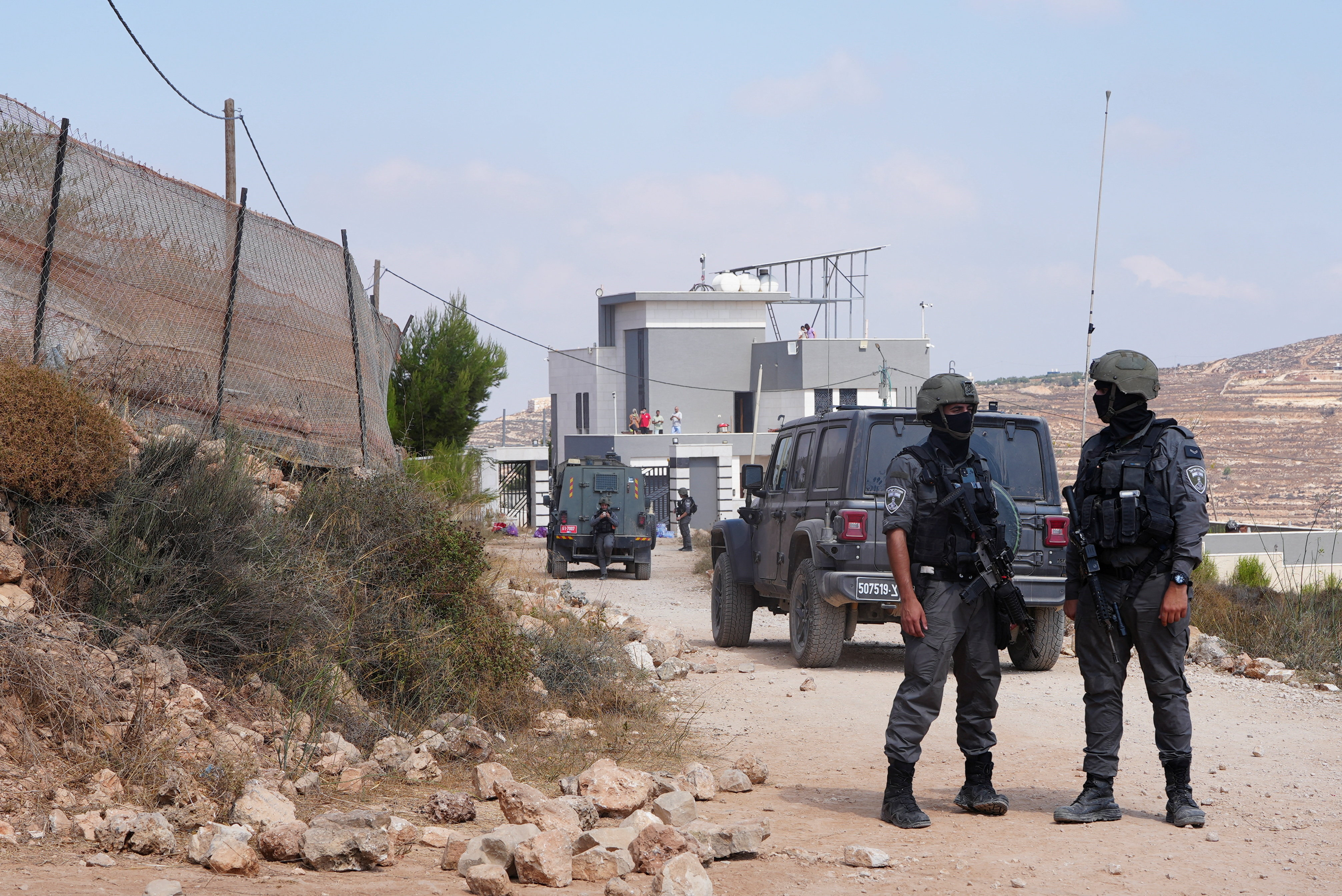 Members of the Israeli security forces stand guard near a Palestinian house, which was besieged by Israeli settlers, in Qusra, in the Israeli-occupied West Bank, August 14, 2026. REUTERS/Ali Sawafta