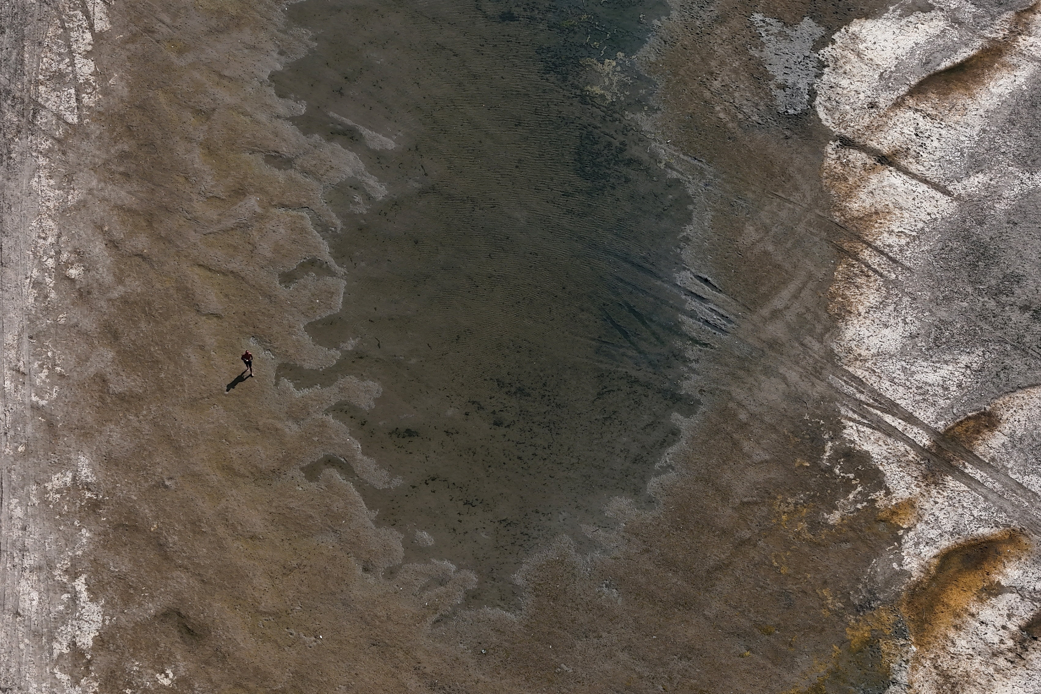 A drone view of a man walking on exposed parts of the riverbed of the Danube River at record-low water levels, in Ruse, Bulgaria, August 13, 2026. REUTERS/Stoyan Nenov