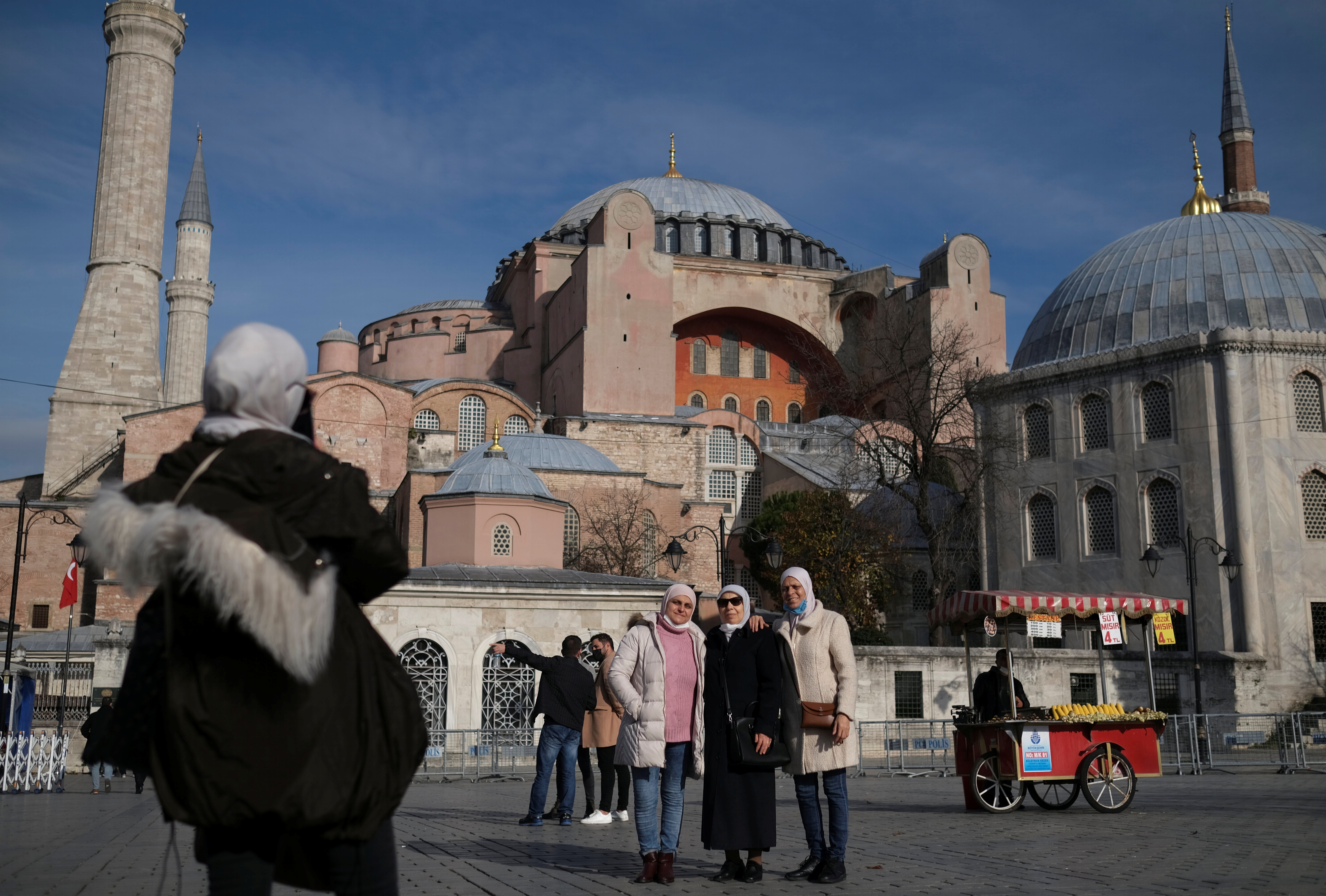 Tourists pose with Ayasofya-i Kebir Camii or Hagia Sophia in Istanbul