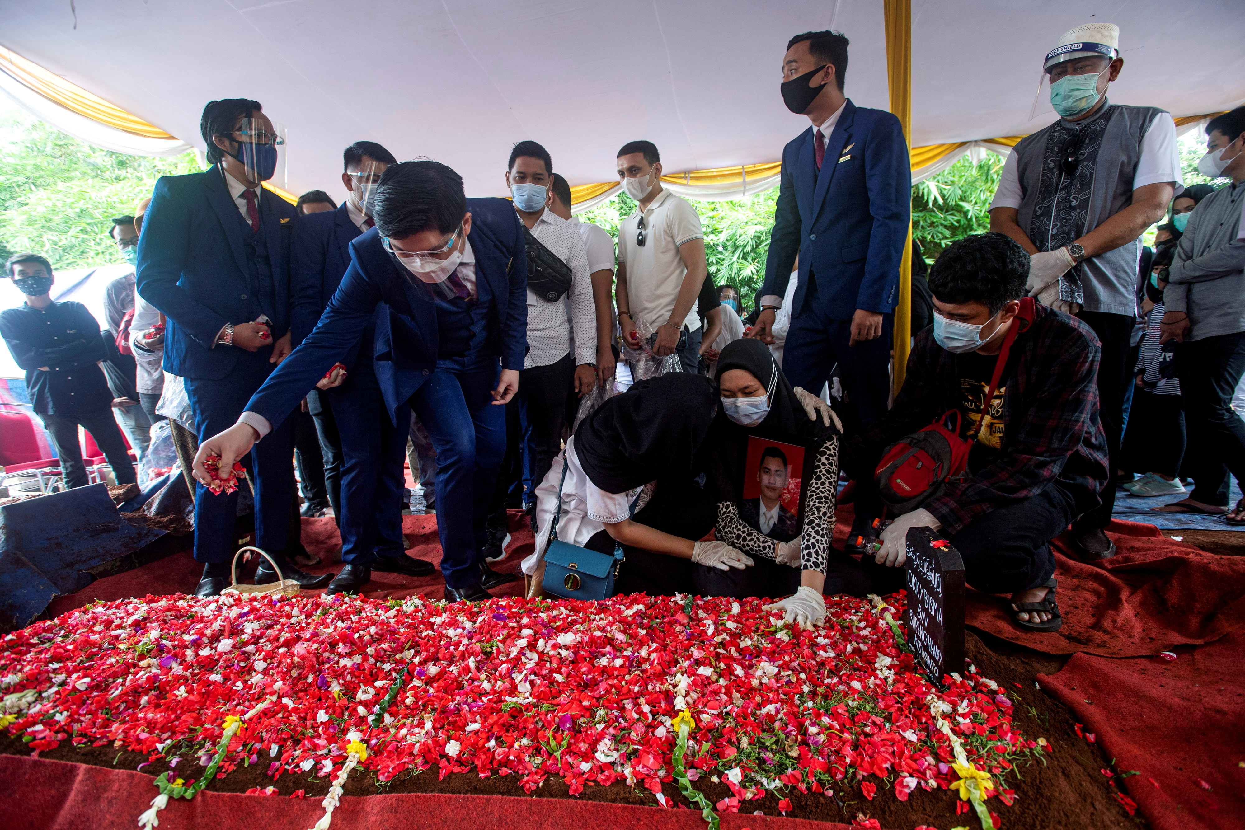 Wife of Okky Bisma, a flight attendant of Sriwijaya Air flight SJ 182 which crashed into Java sea, reacts at her husband's grave during the funeral in Jakarta