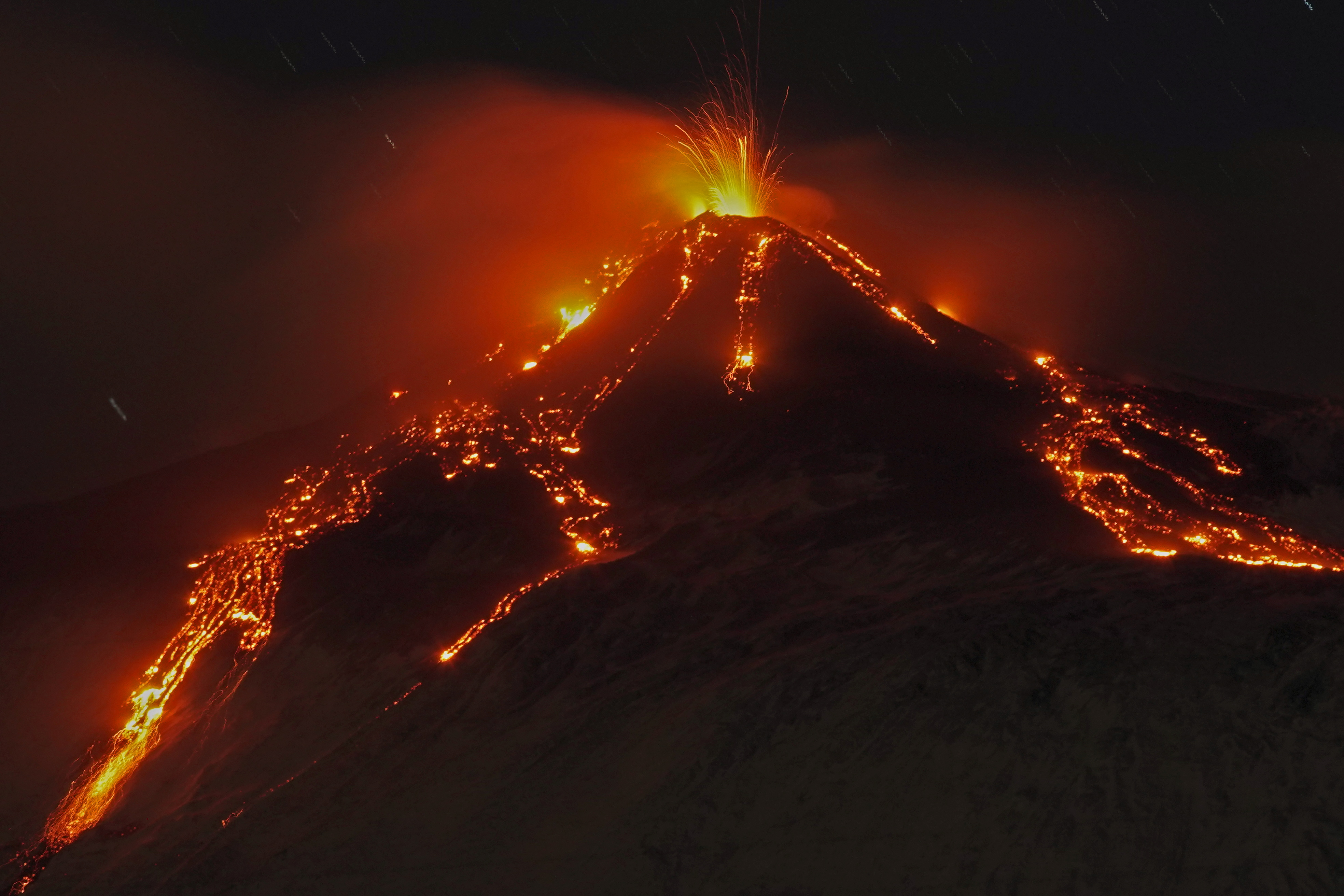 An eruption from Mount Etna lights up the sky during the night, seen from Fornazzo