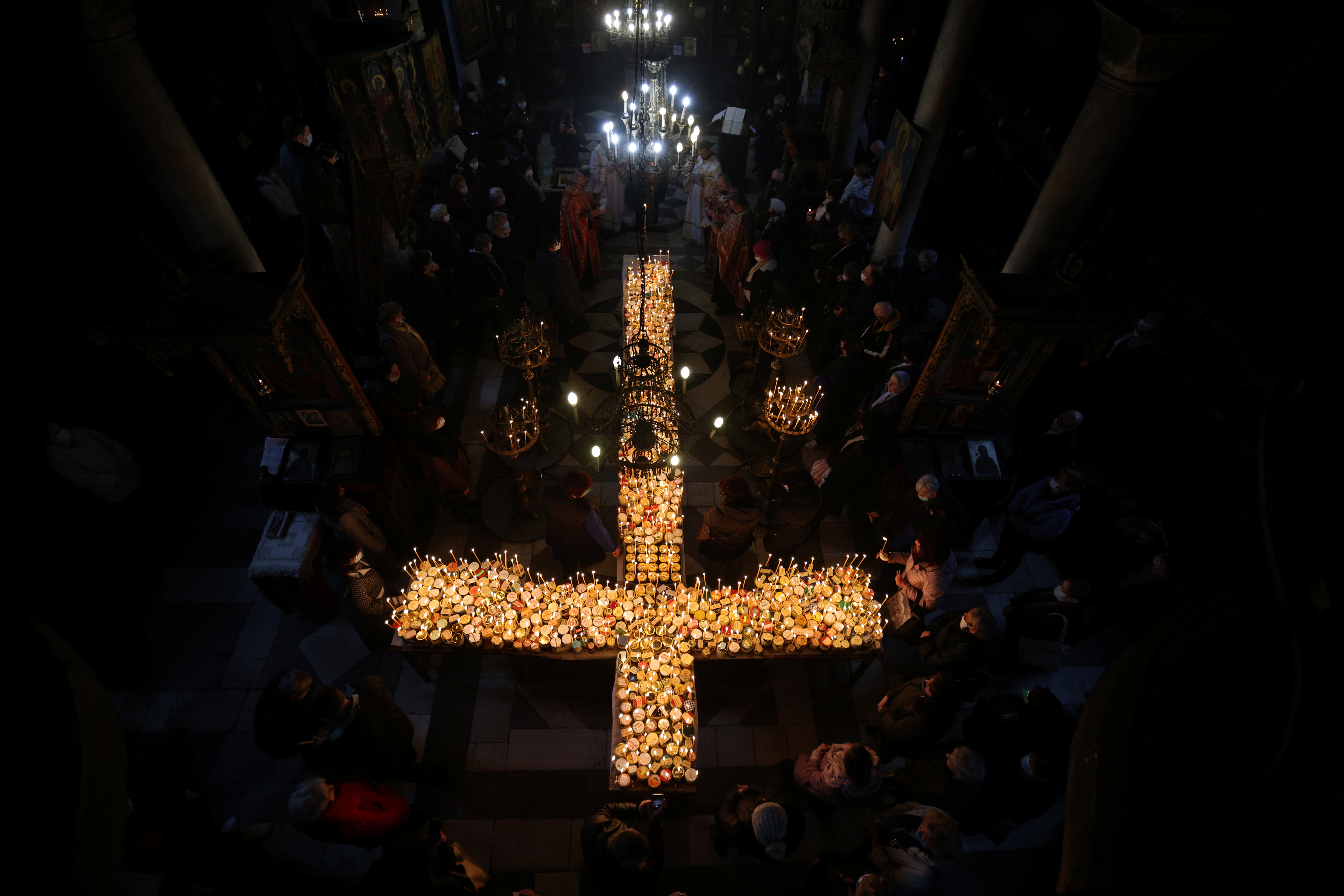 Worshippers gather around candles stuck to jars with honey during a religious mass in Blagoevgrad