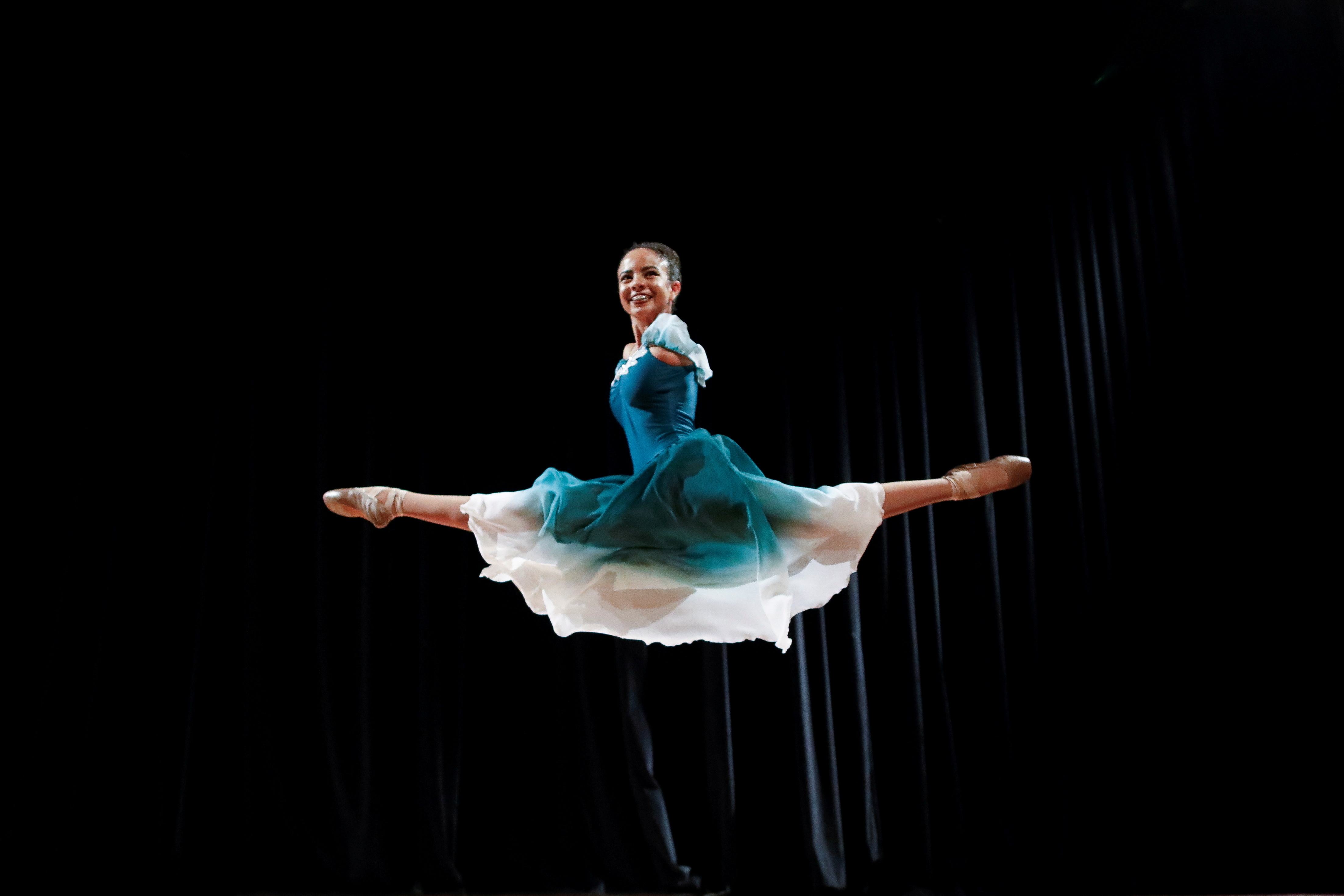 Vitoria Bueno, a 16-year-old dancer whose genetic condition left her without arms, jumps during a solo performance on stage at the Inatel Theater in Santa Rita do Sapucai