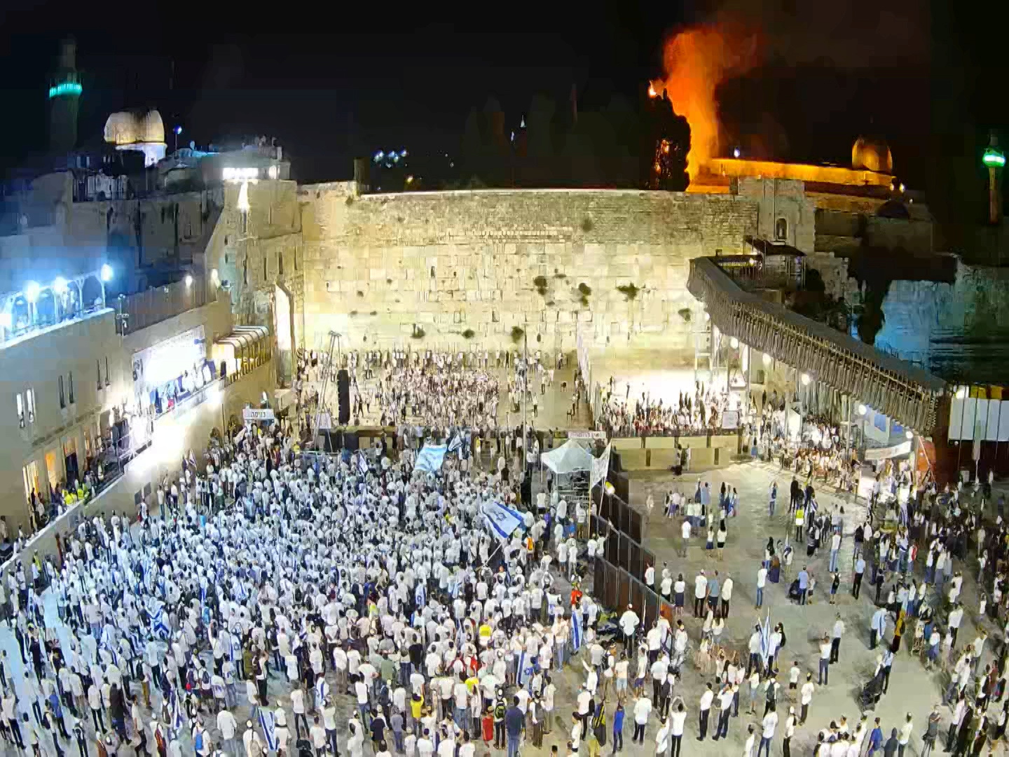 Israelis gather at the Western Wall as a blaze is seen in the background at the compound that houses al-Aqsa mosque in Jerusalem's Old City, is this still image taken from video
