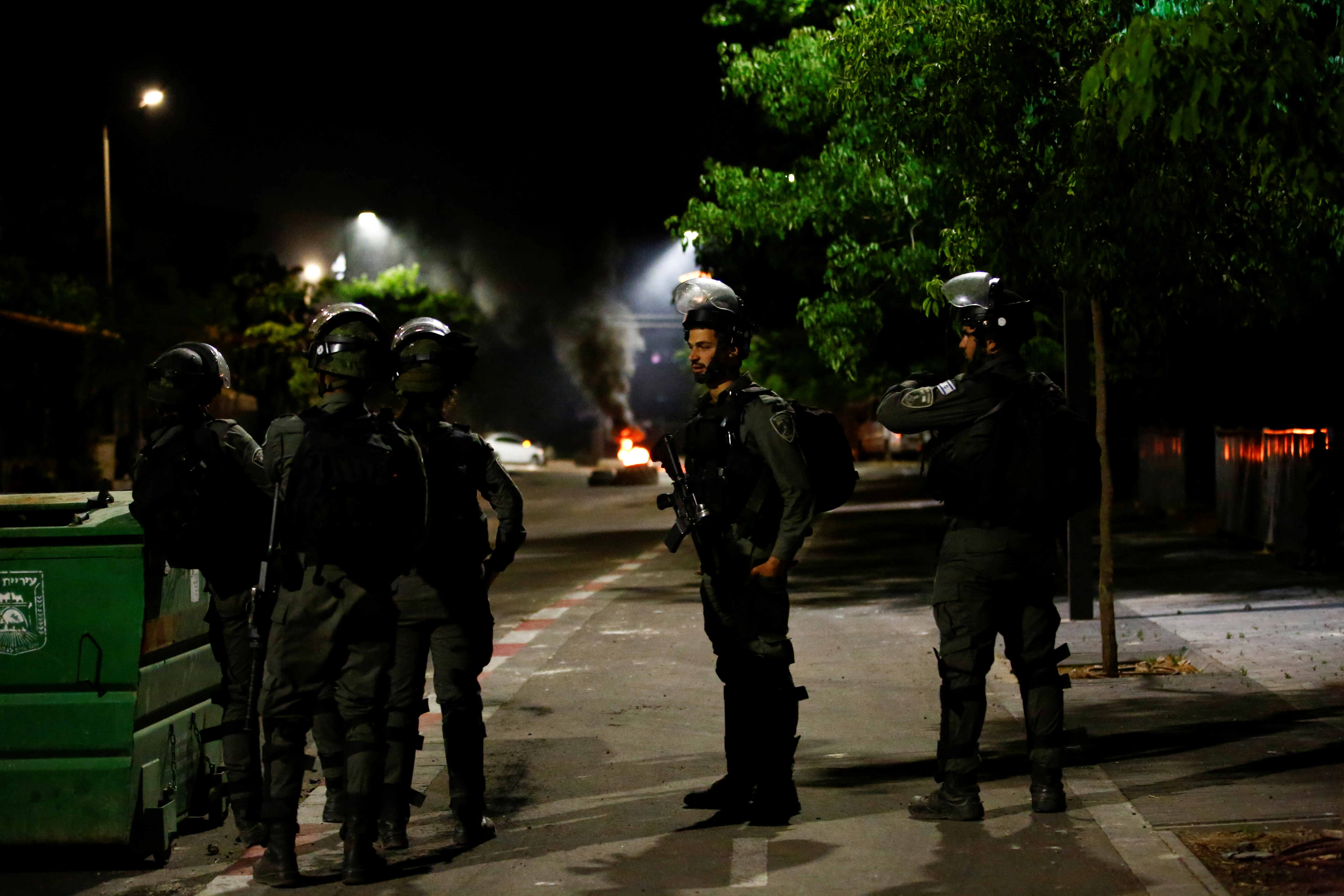 Israeli Border Police force members stand near burning tires by one of the entrances to the Arab-Jewish town of Lod