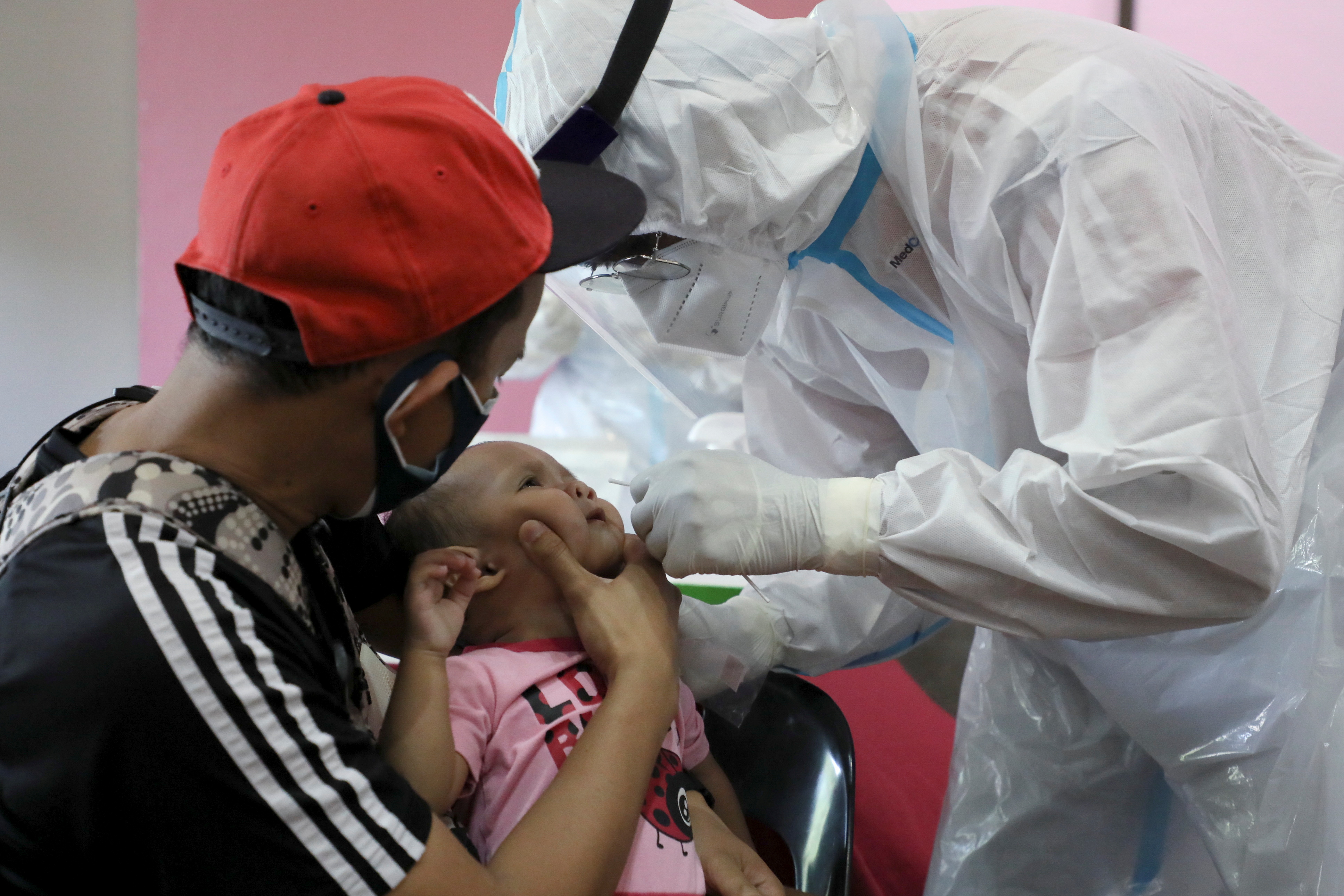 Medical worker collects a swab sample from a baby to be tested for the coronavirus disease (COVID-19) in Cyberjaya