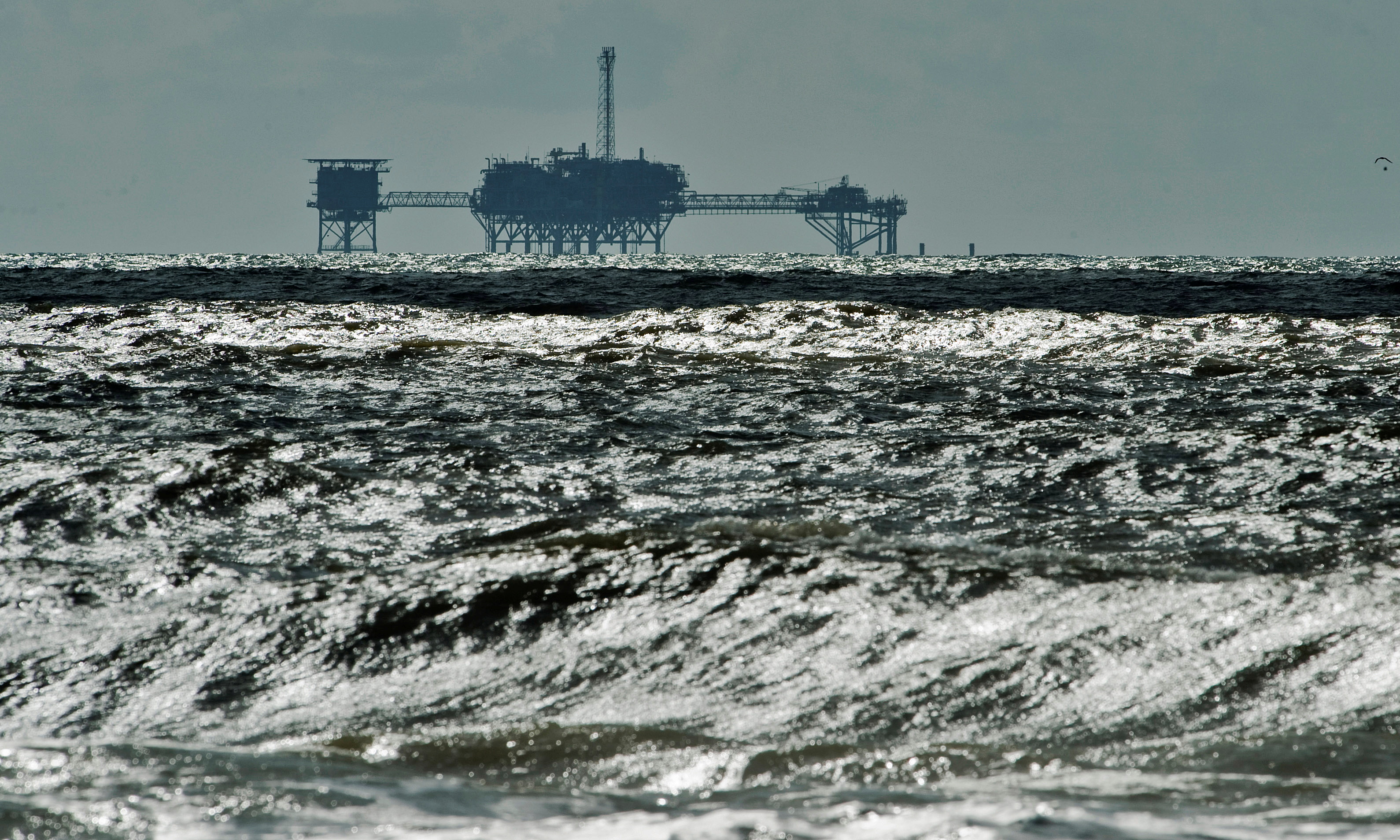 FILE PHOTO: An oil and gas drilling platform stands offshore as waves churned from Tropical Storm Karen come ashore in Dauphin Island, Alabama