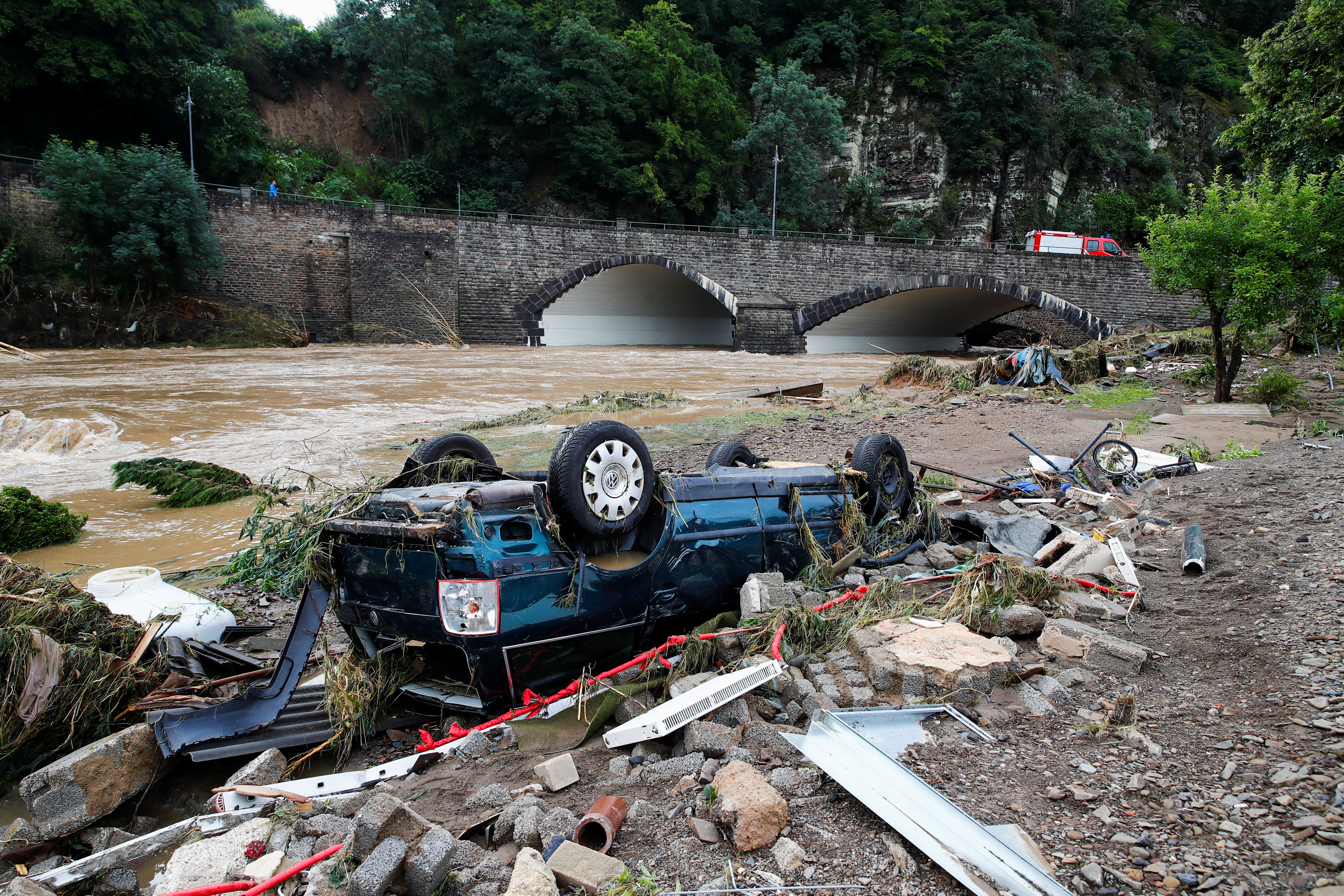 A destroyed car is seen next to the Ahr river in Schuld