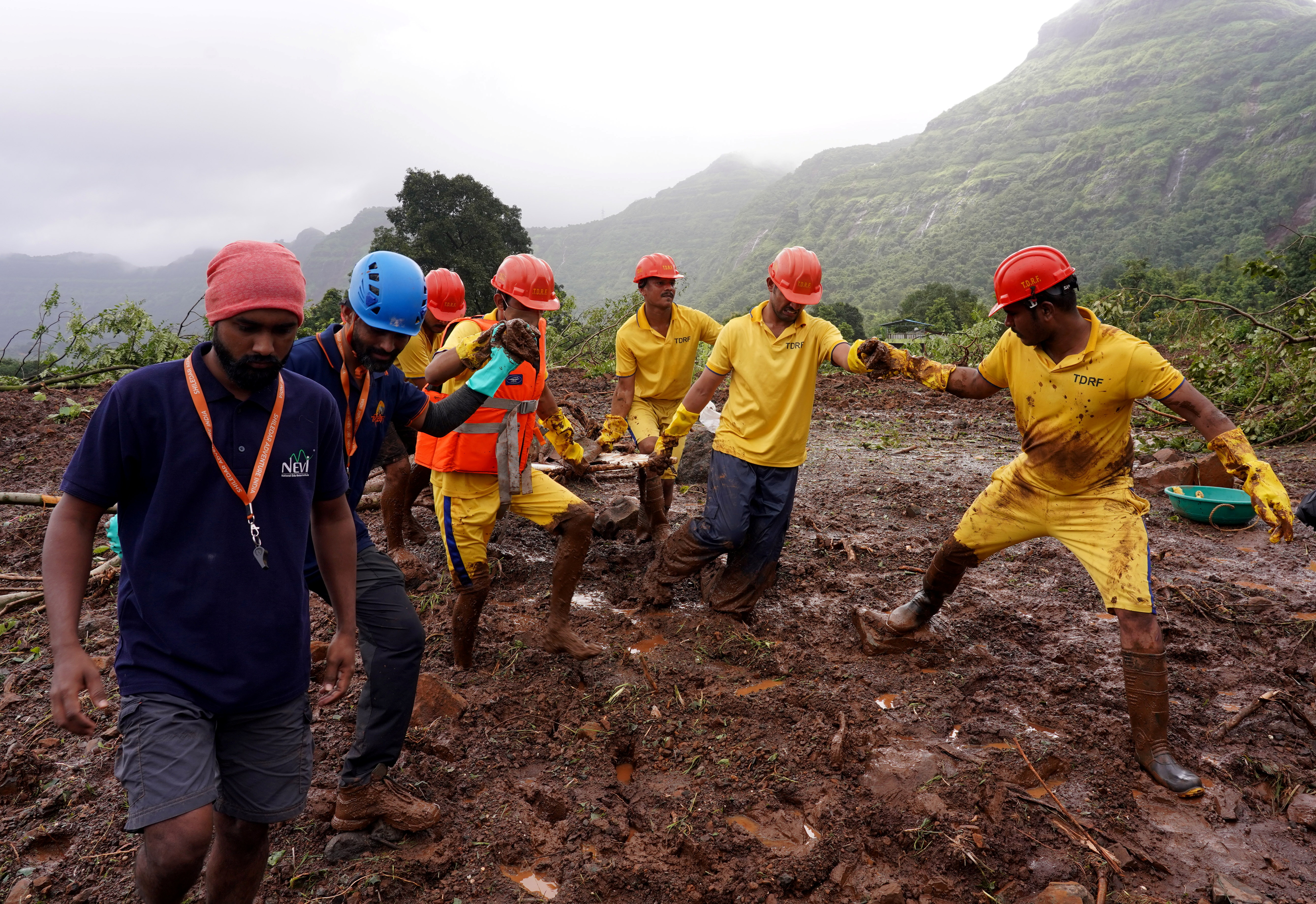 Rescue workers carry the body of a victim after recovering it from a site of a landslide in Mahad