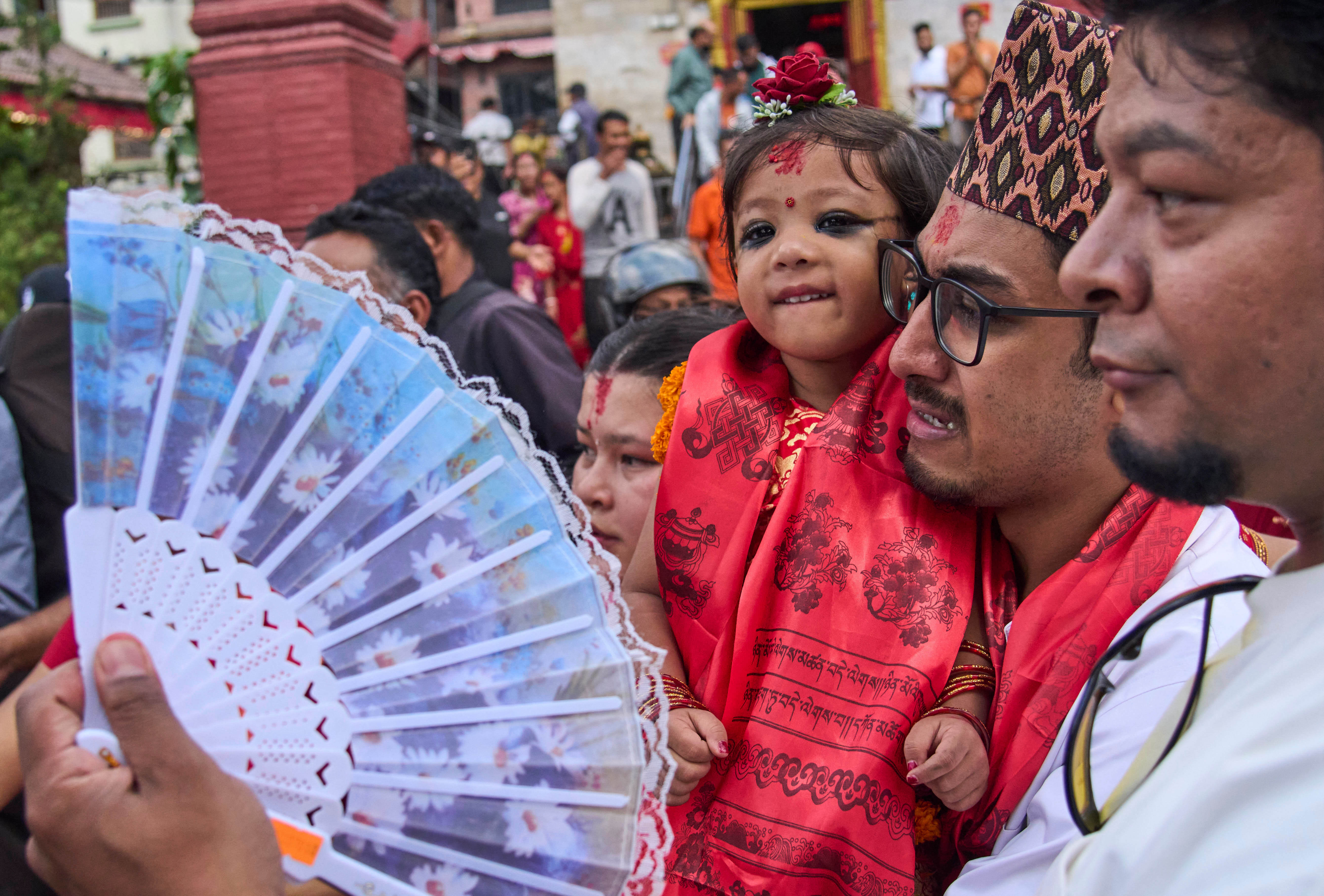Nepal's newly appointed living goddess, Kumari Aryatara Shakya, is carried by her father as they walk towards Kumari Ghar, the temple palace where she will be residing in Kathmandu, Nepal, Tuesday, Sept. 30, 2025. (AP Photo/Niranjan Shrestha)