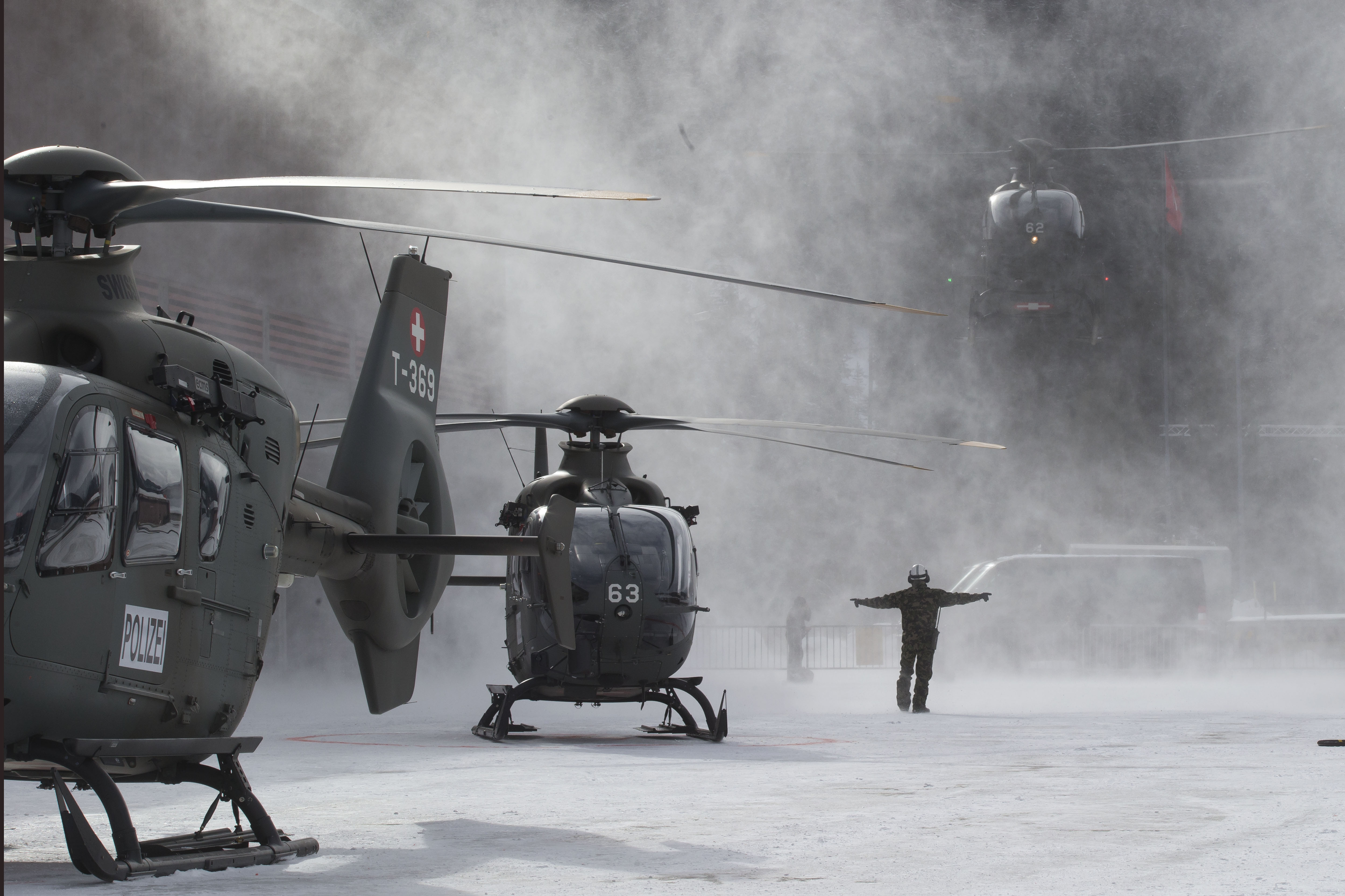 A Swiss army airman guides a EC 635 helicopter for landing at an army base in Davos