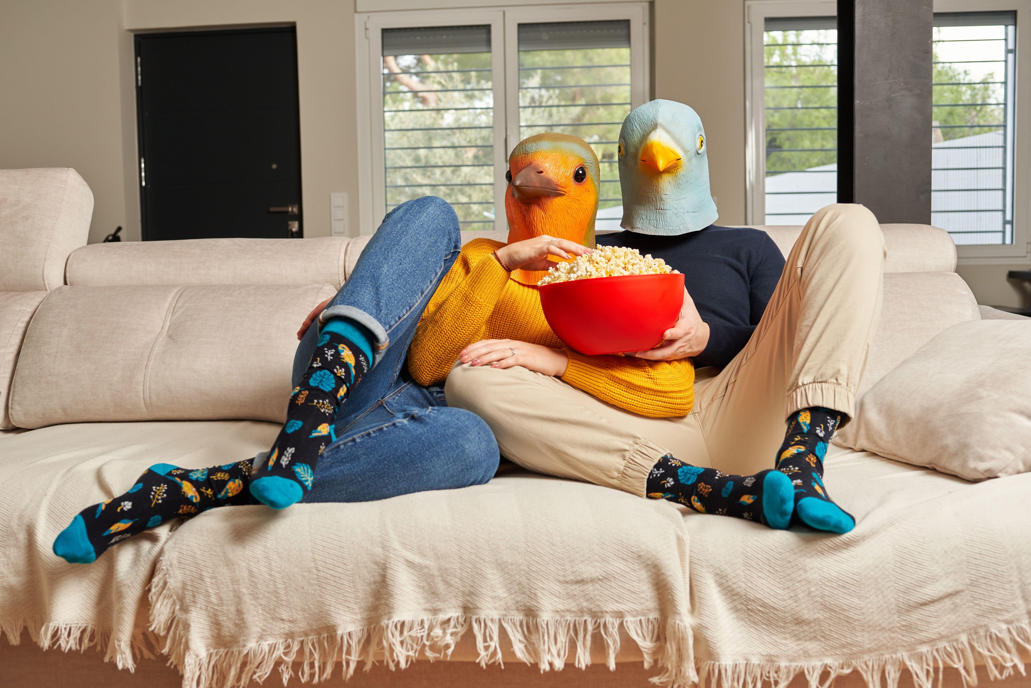 A young couple dressed in bird masks eat popcorn on the sofa at home while watching series on streaming platforms,Image: 671031052, License: Royalty-free, Restrictions: , Model Release: no, Credit line: Jose Martinez / Alamy / Profimedia