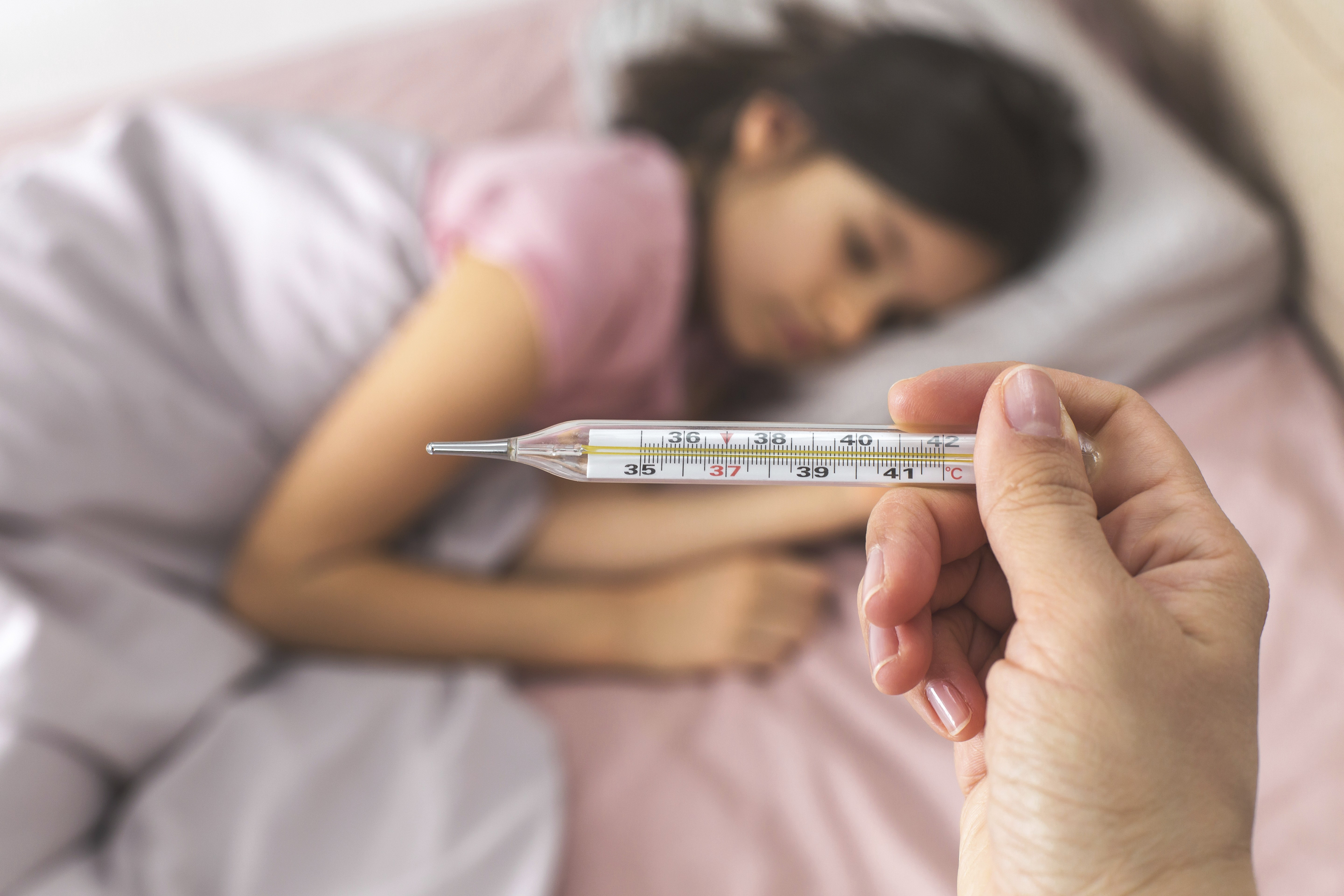 Thermometer with a high temperature reading, while a sick child lies in bed under a blanket, looking unwell,Image: 1053291544, License: Royalty-free, Restrictions: , Model Release: yes, Credit line: Evgeniia Gordeeva / imageBROKER / Profimedia