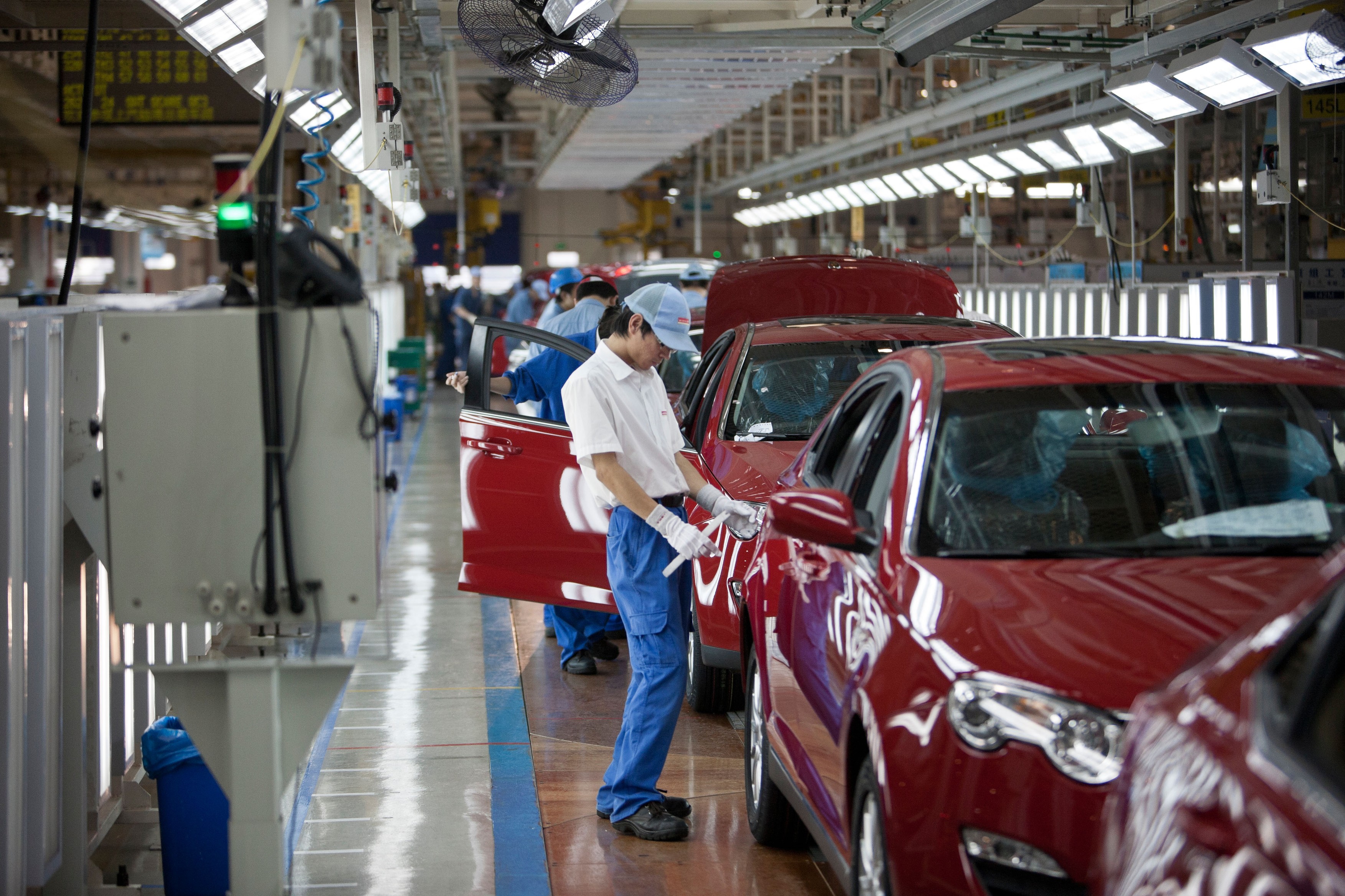 Chinese workers check the quality of Roewe sedans at a car factory of the