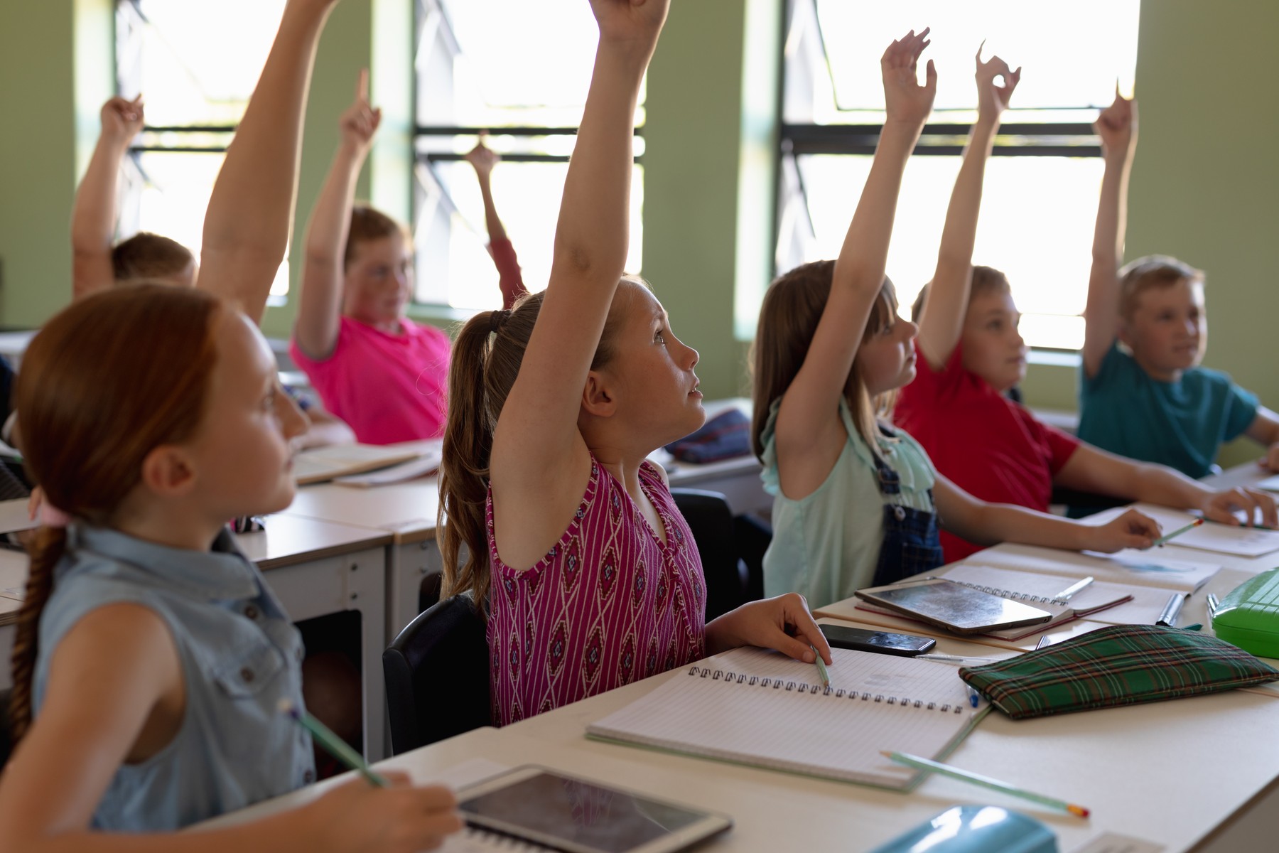Side view of a diverse group of school children sitting at desks