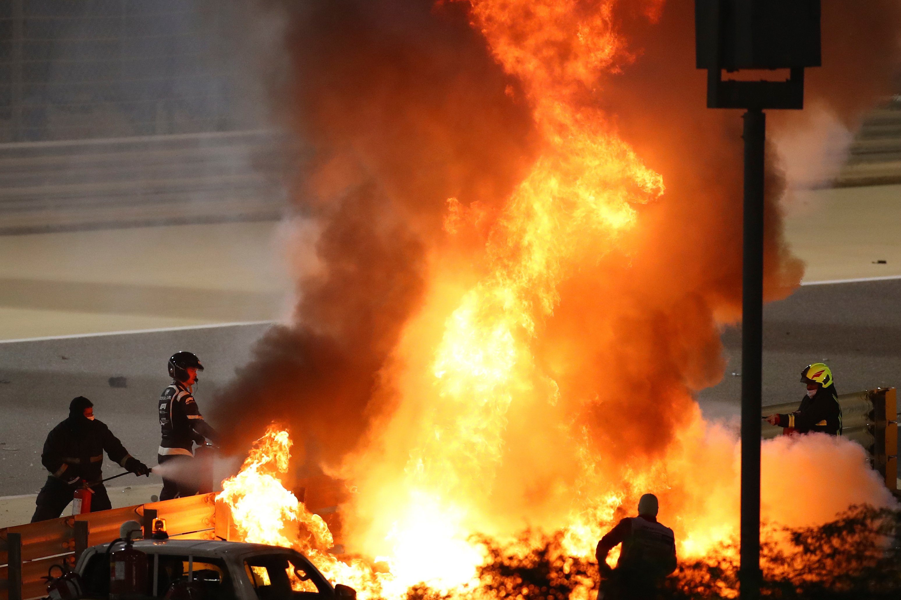 FILE - Staff extinguish flames from Haas driver Romain Grosjean's car after a crash during the Formula One race in Bahrain International Circuit in Sakhir, Bahrain, in this Nov. 29, 2020, file photo. (Brynn Lennon/Pool via AP, File)
