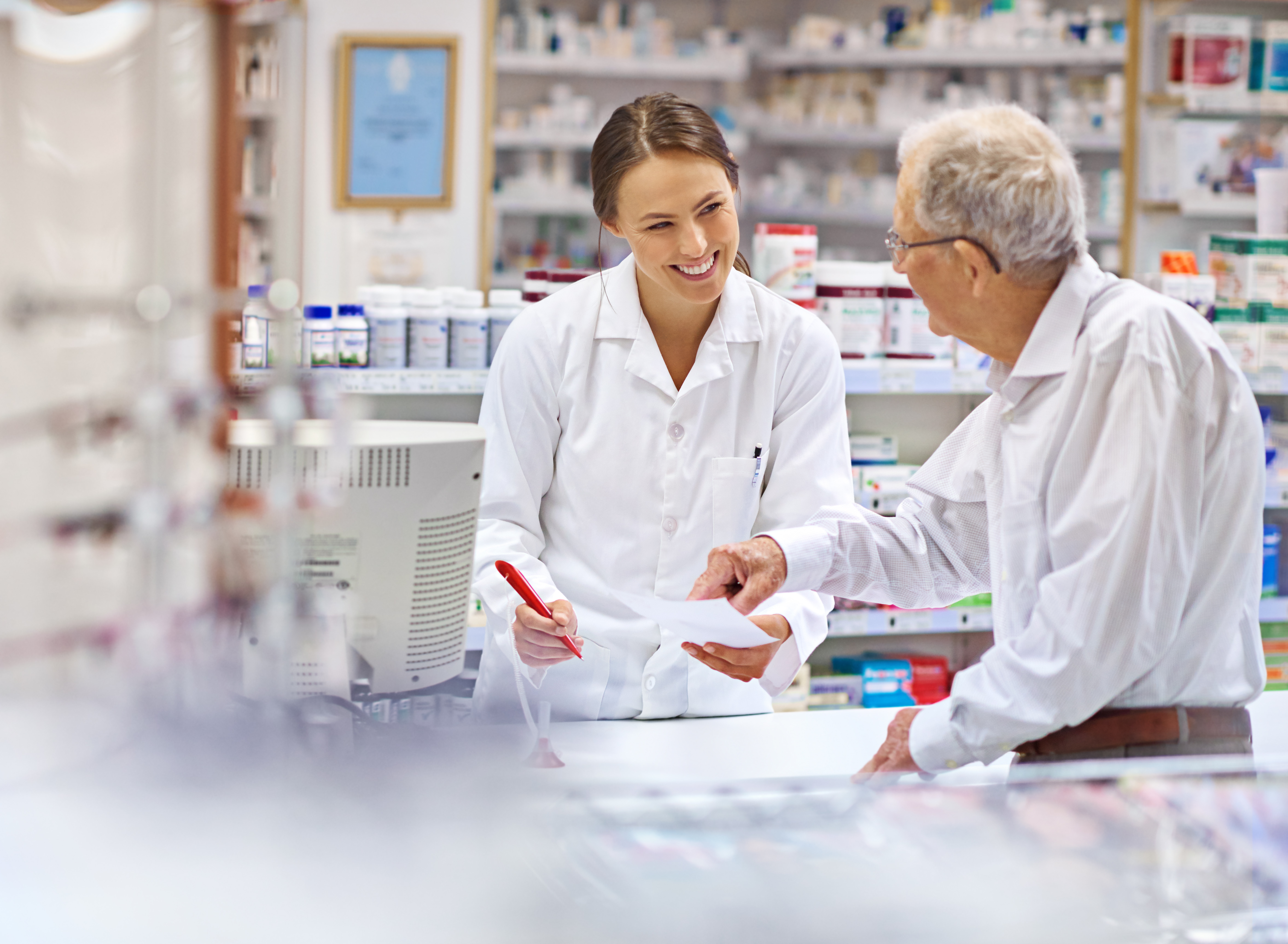Shot of a young pharmacist helping an elderly customer at the prescription counter