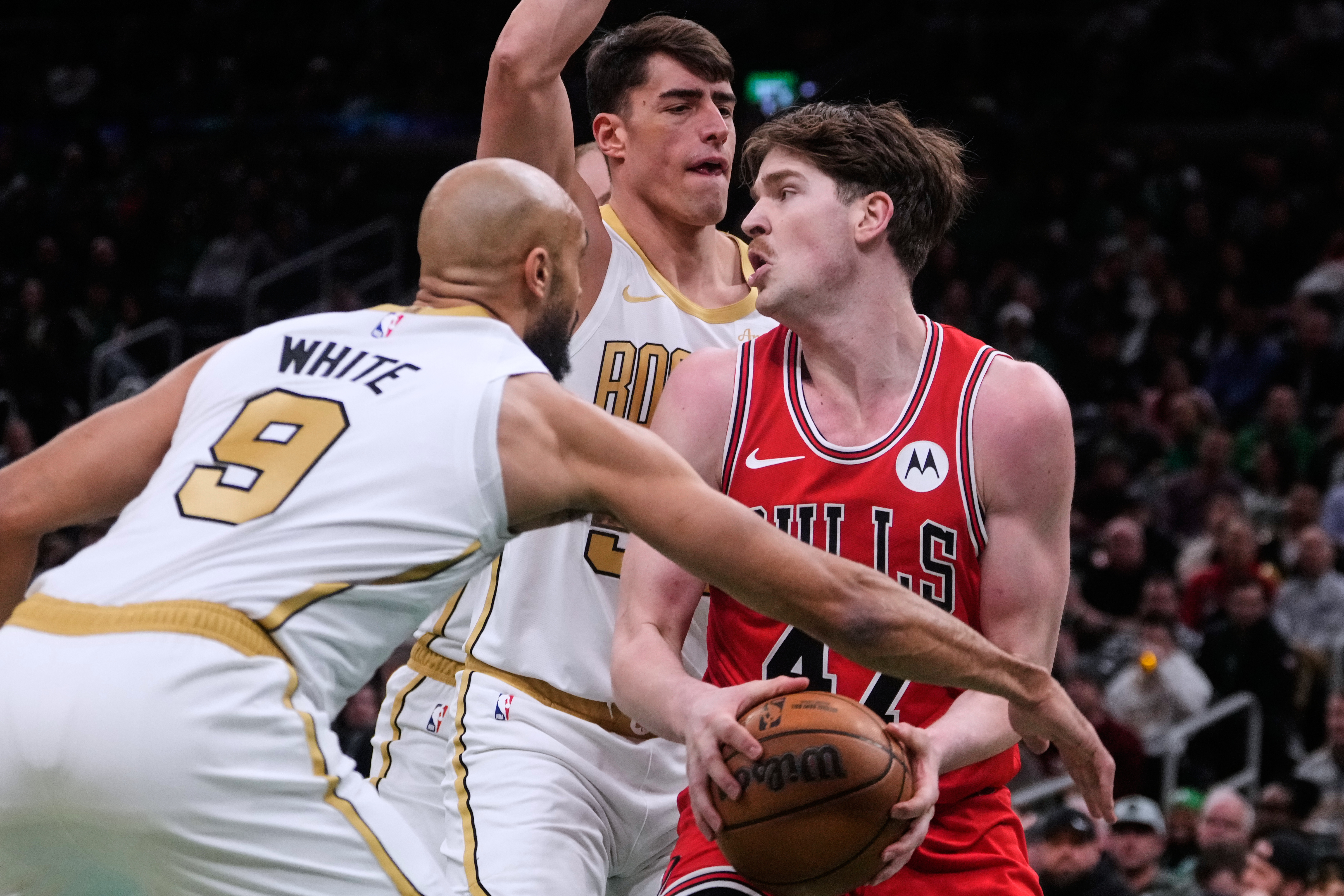 Chicago Bulls center Lachlan Olbrich (47) looks to pass while pressured by Boston Celtics guard Derrick White (9) and Boston Celtics center Luka Garza, rear, during the first half of an NBA basketball game, Monday, Jan. 5, 2026, in Boston. (AP Photo/Charl