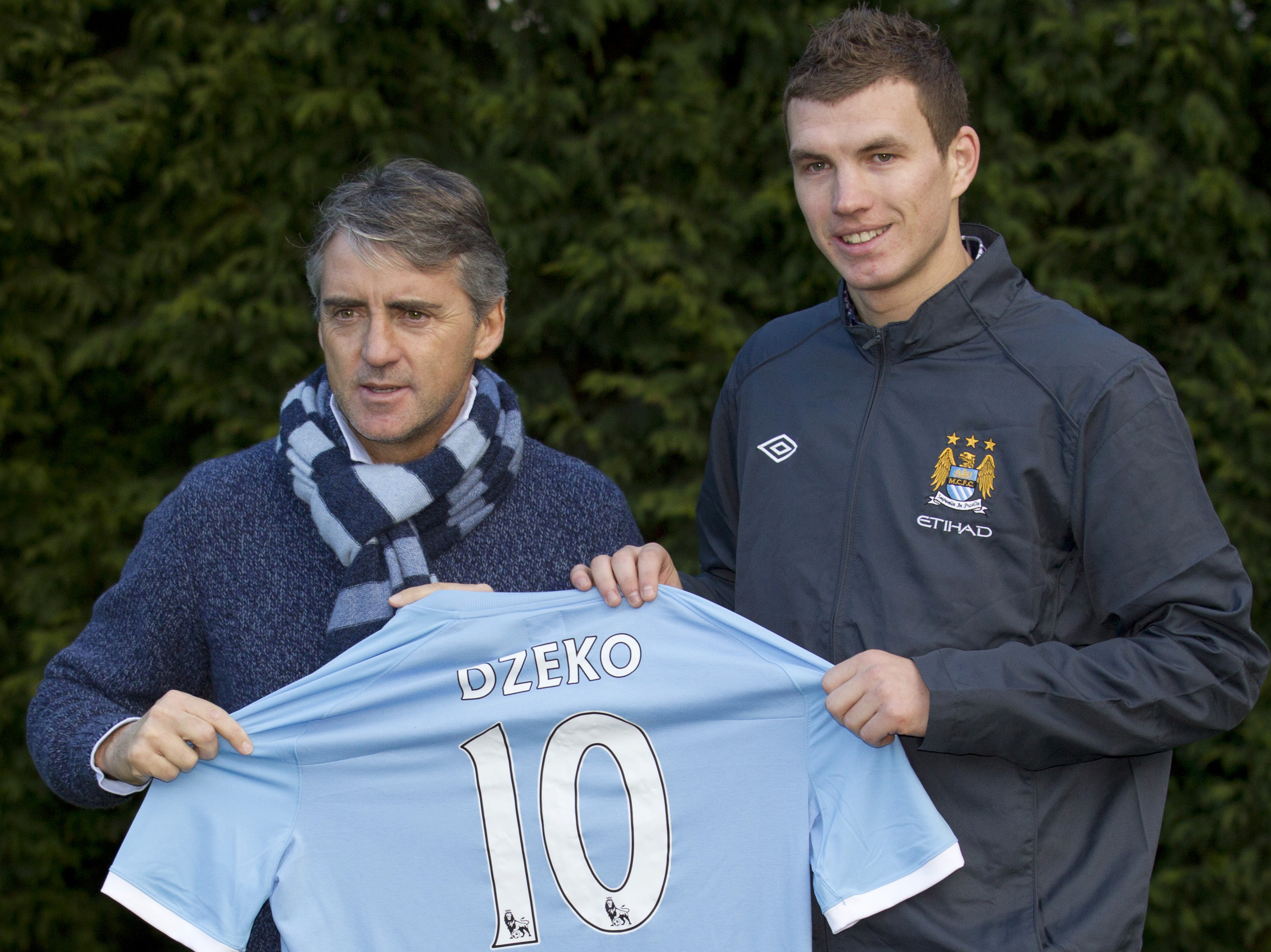 Manchester City's new Bosnian striker Edin Dzeko, right, poses for photographs with his manager Roberto Mancini at the club's Carrington training ground, Manchester, England, Tuesday Jan. 11, 2011. (AP Photo/Jon Super)