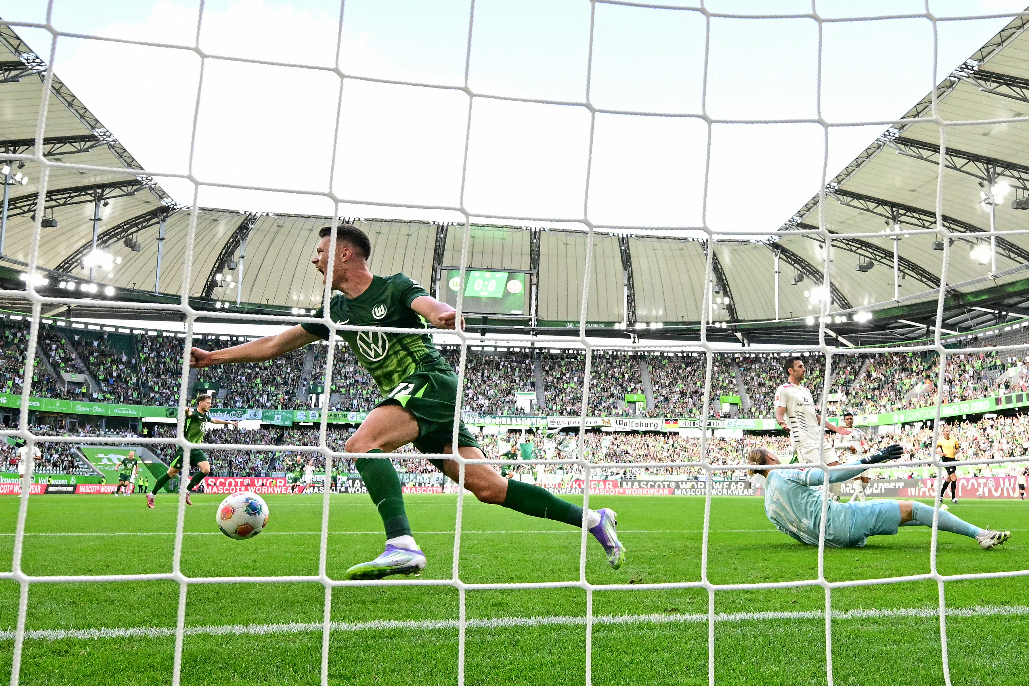Wolfsburg's German forward #17 Dzenan Pejcinovic (L) celebrates after his teammate Aaron Zehnter (not in picture) scores the opening past Mainz' German goalkeeper #27 Robin Zentner during the German first division Bundesliga f Pejčinović etween VfL Wol