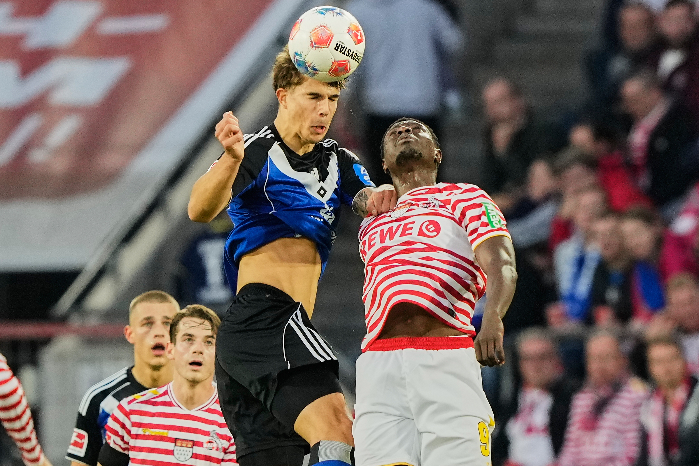 Hamburg's Luka Vuskovic and Cologne's Ragnar Ache jump for the ball during the German Bundesliga soccer match between 1. FC Koeln and Hamburger SV in Cologne, Germany, Sunday, Nov. 2, 2025. (AP Photo/Martin Meissner)