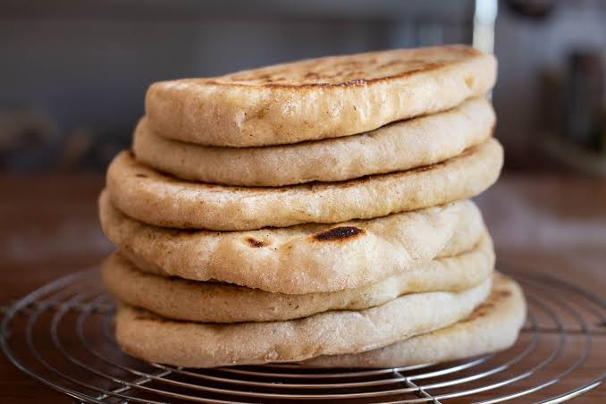 A stack of freshly made bazlama bread, a traditional Turkish flatbread, on a cooling rack.
