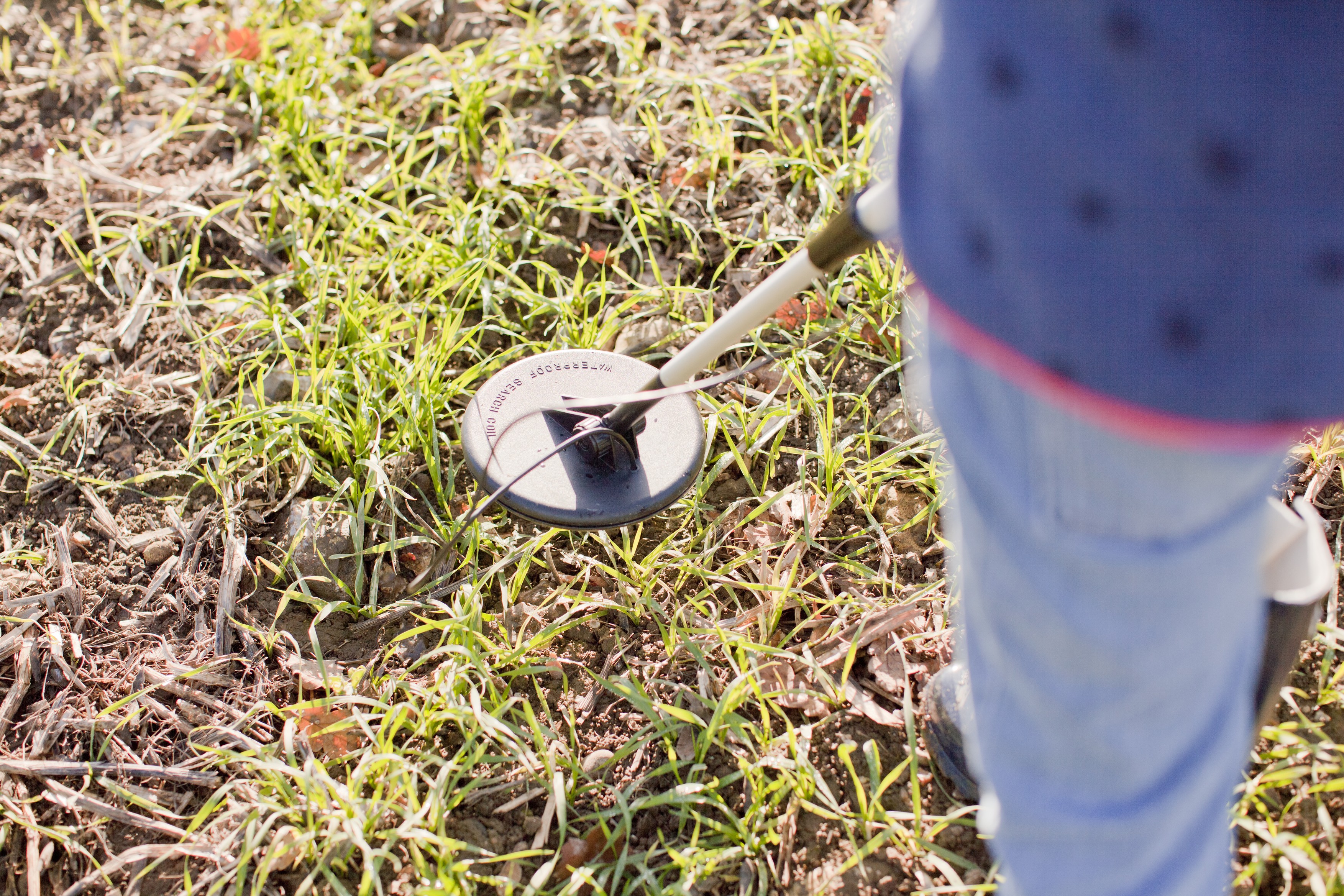 Cropped view of girl using metal detector in field