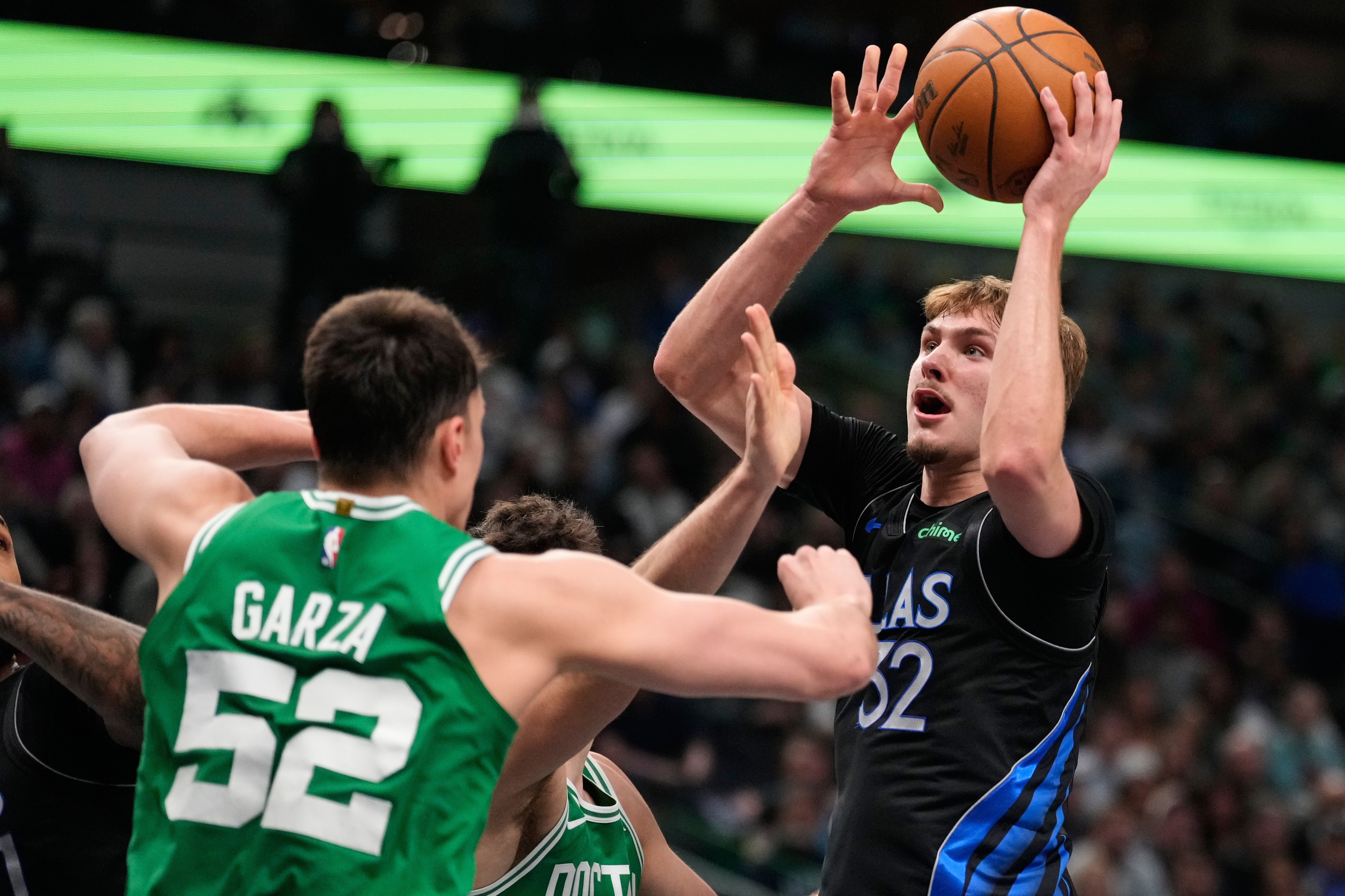 Dallas Mavericks' Cooper Flagg (32) takes a shot as Boston Celtics' Luka Garza (52) and Hugo Gonzalez, rear, defend in the first half of an NBA basketball game Tuesday, Feb. 3, 2026, in Dallas. (AP Photo/Tony Gutierrez)