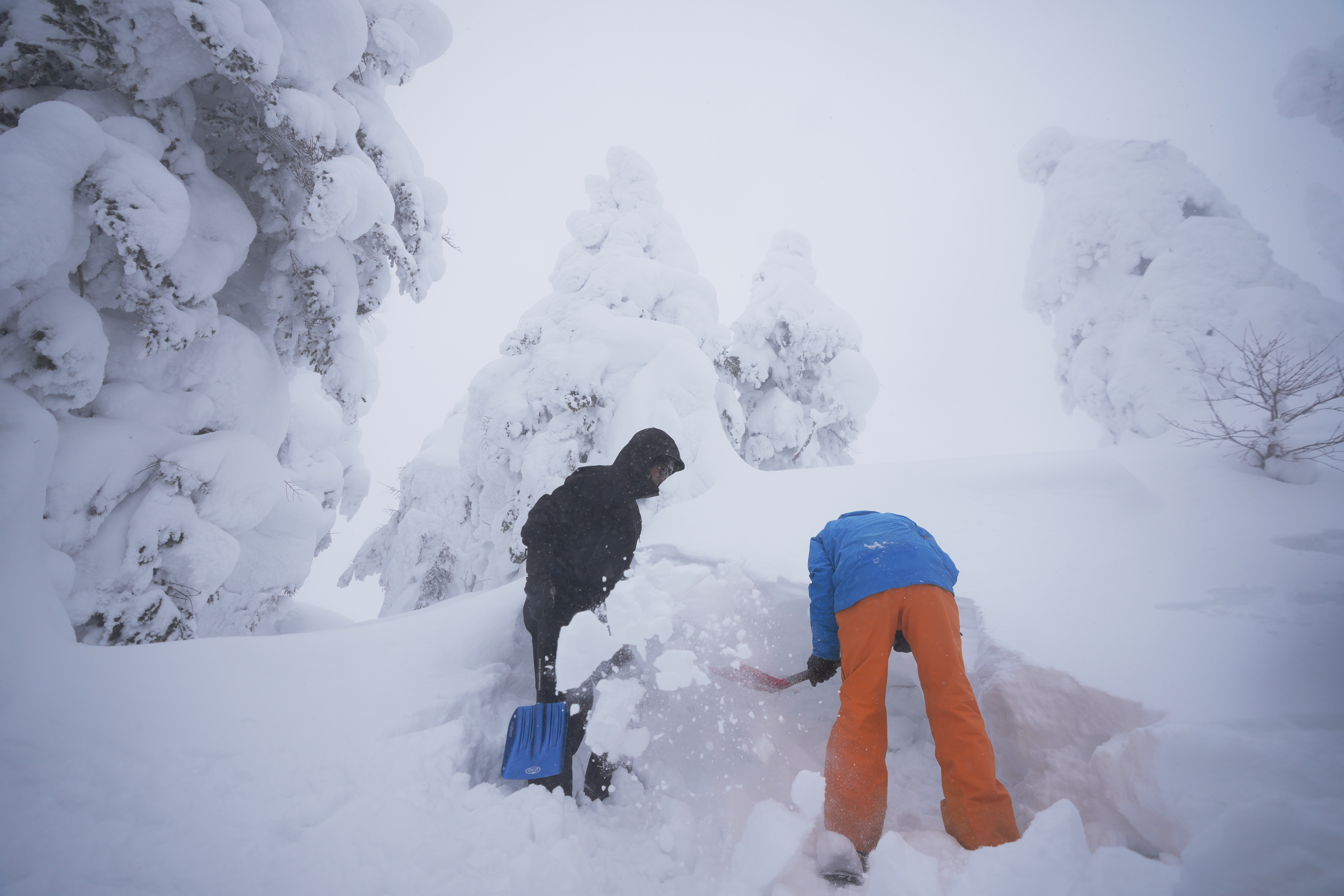 An instructor, right, shows how to make a snow cave for an emergency encampment in freezing temperature to one of the group members during a winter mountain climbing training tour at the Zao mountains near Yamagata