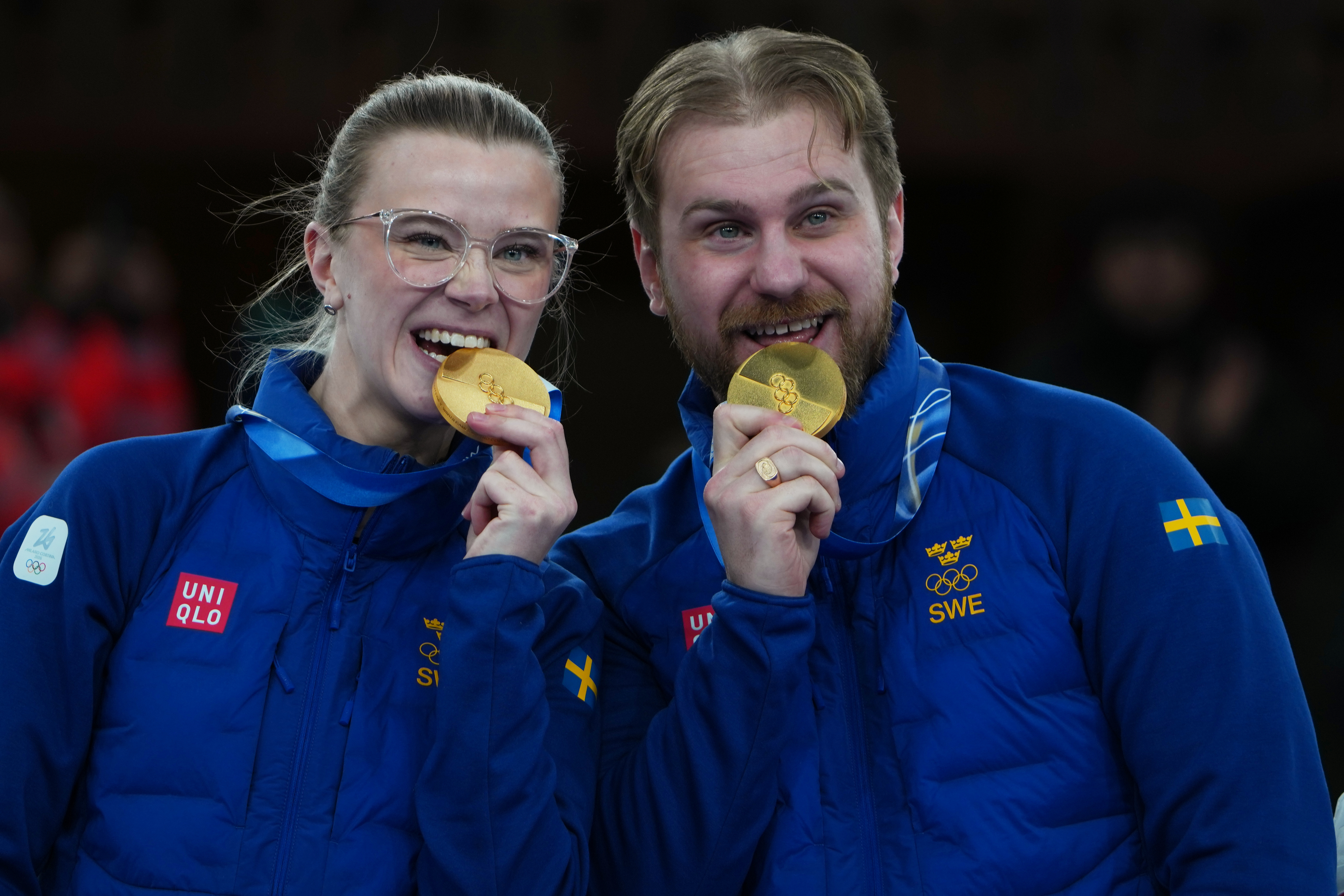 1770753390-Sweden's Isabella Wranaa and Rasmus Wranaa celebrate on the podium after winning the gold medal match of the mixed doubles curling at the 2026 Winter Olympics, in Cortina d'Ampezzo, Italy, Tuesday, Feb. 10, 2026. (AP Photo/Misper Apawu)