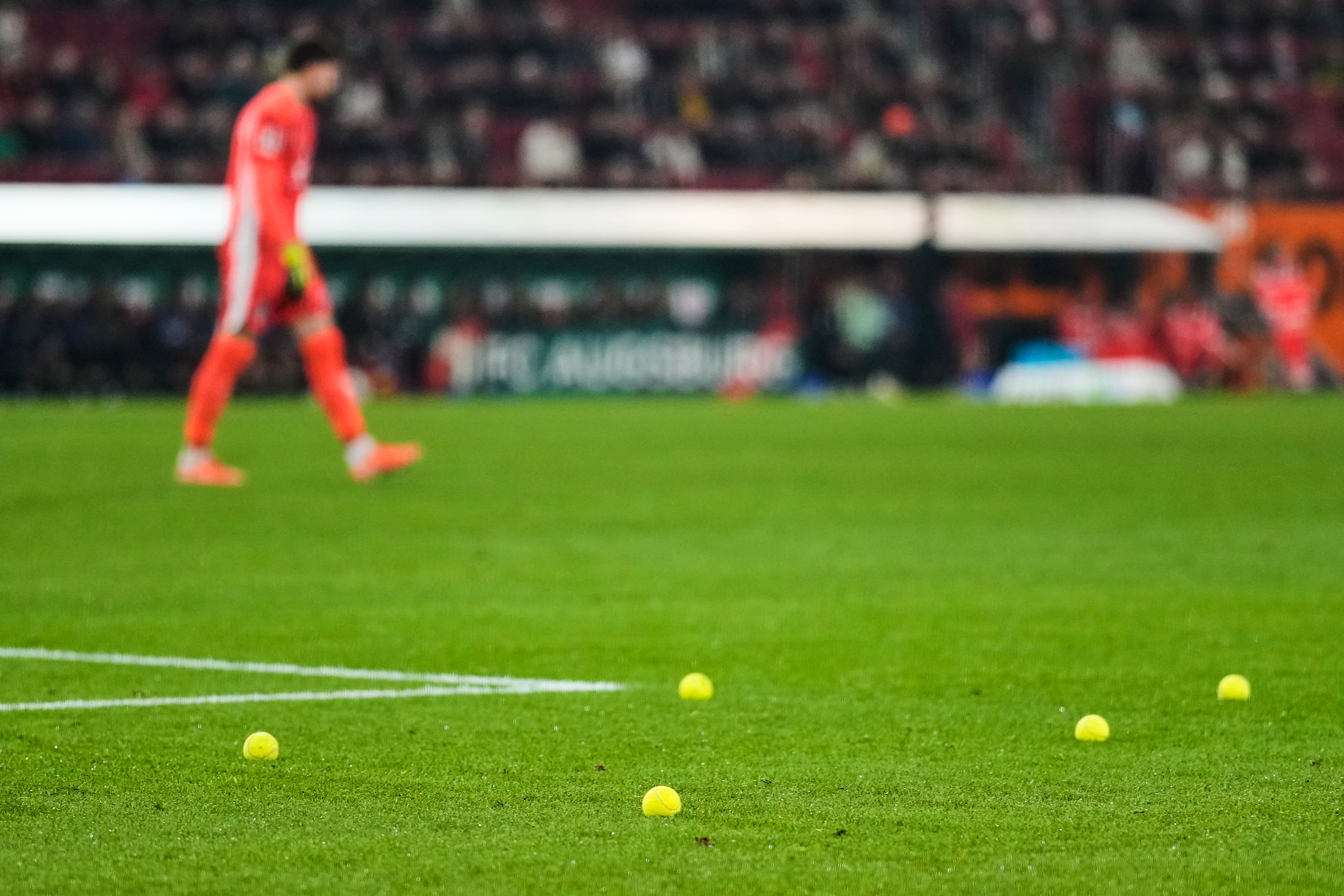 Tennis balls lie on the pitch after fans threw them to protest against the German Soccer Federation during the Bundesliga soccer match between FC Augsburg and Borussia Dortmund in Augsburg, Germany, Oct. 31, 2025. (AP Photo/Matthias Schrader)