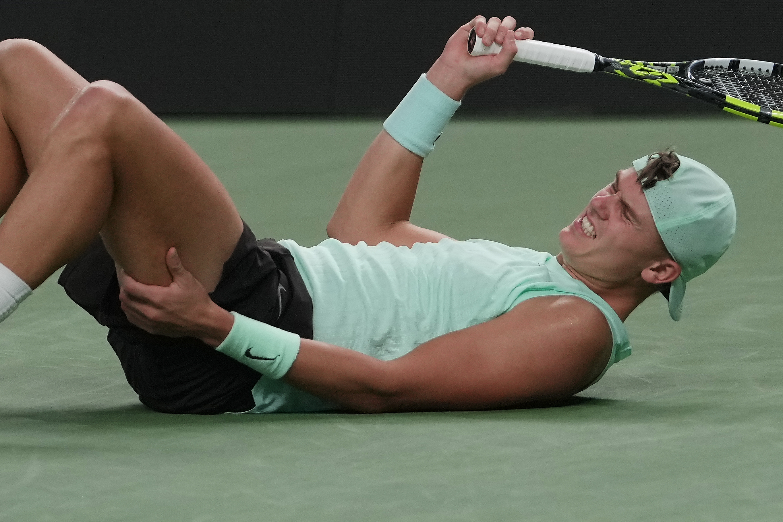 Holger Rune of Denmark grimaces as he suffers from leg cramps during the men's singles quarterfinals match against Valentin vacherot of Monaco, at the Shanghai Masters tennis tournament at Qizhong Forest Sports City Tennis Center, in Shanghai, China, Thur