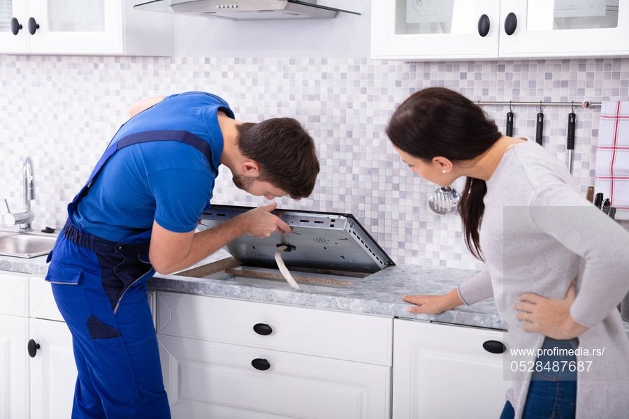 Woman Looking At Serviceman In Uniform Fixing Induction Stove In The Kitchen,Image: 528487687, License: Royalty-free, Restrictions: , Model Release: yes, Credit line: Andriy Popov / Panthermedia / Profimedia
