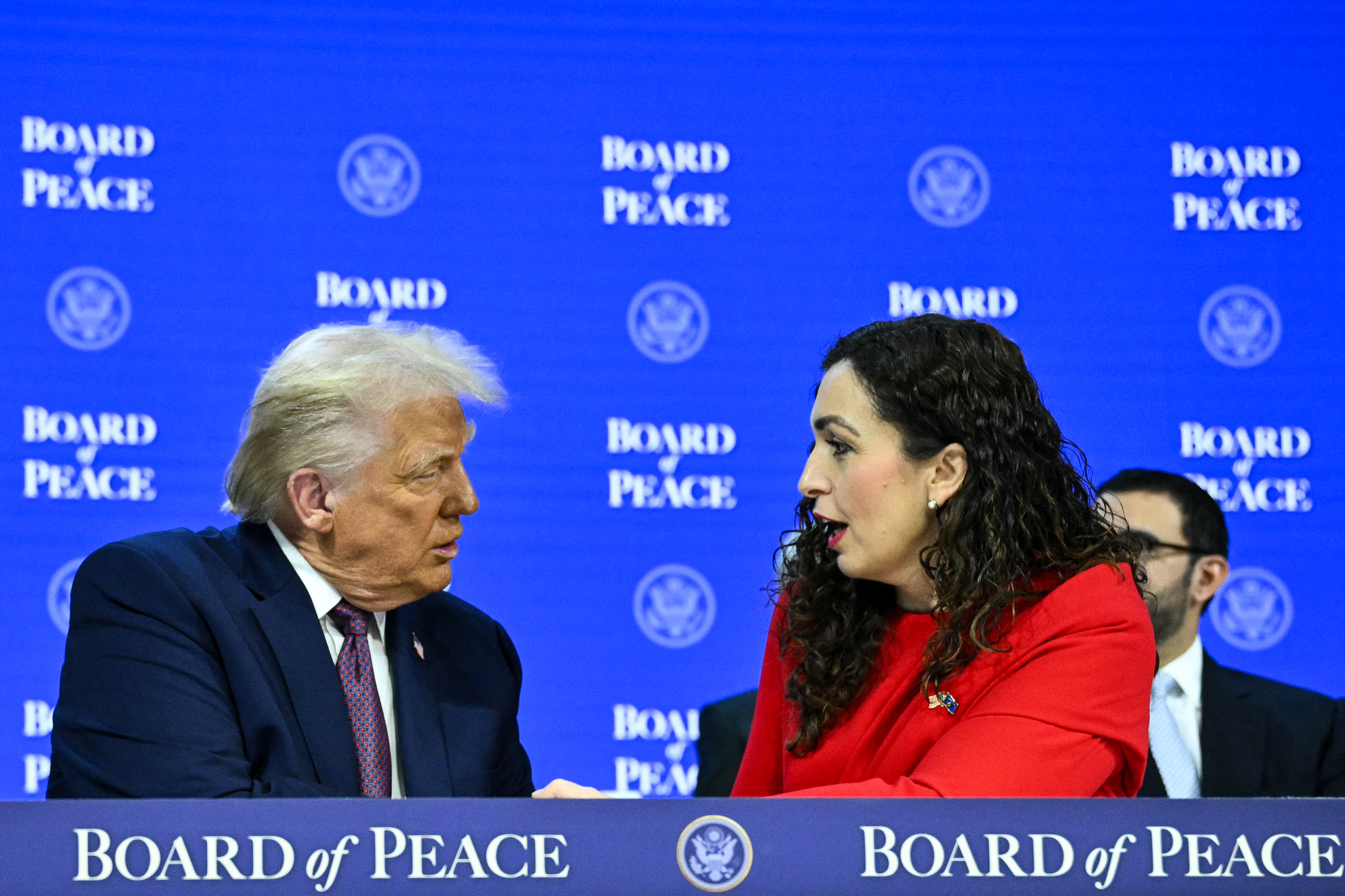 Kosovo's President Vjosa Osmani (R) shakes hands with US Presiden