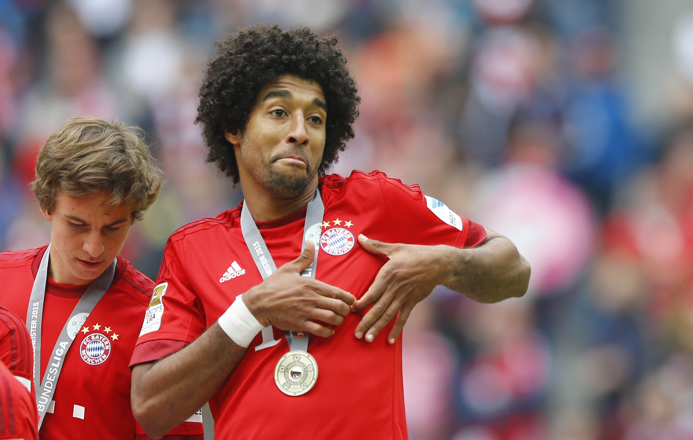 Bayern's Dante from Brazil shows a heart with his hands as his team gets the championship trophy after the German first division Bundesliga soccer match between Bayern Munich and FSV Mainz at the Allianz Arena in Munich, Germany, Saturday, May 23, 2015. (