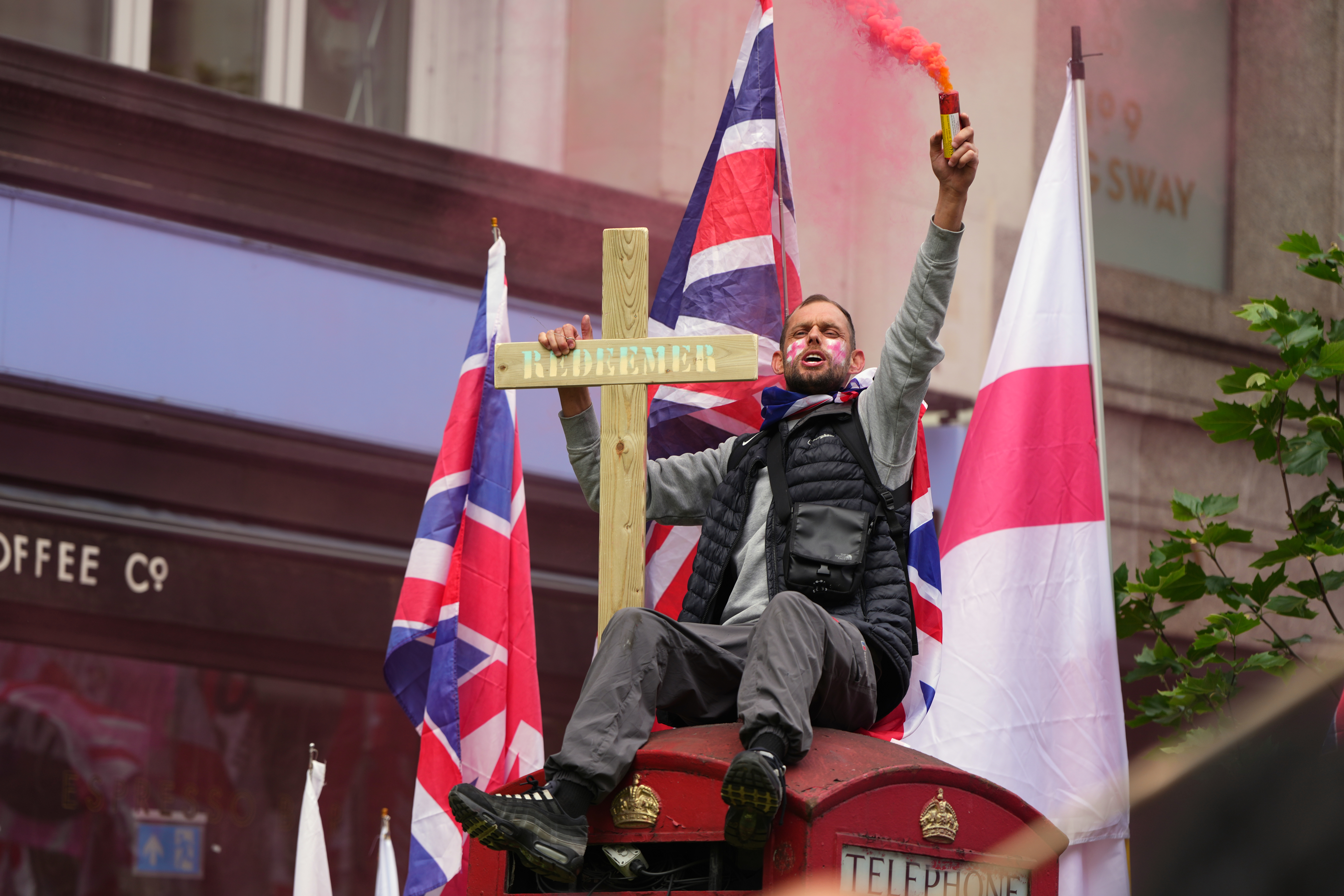 A protester sits on a phone box during the far right Unite the Kingdom march in London, Saturday, May 16, 2026.(AP Photo/Kirsty Wigglesworth)