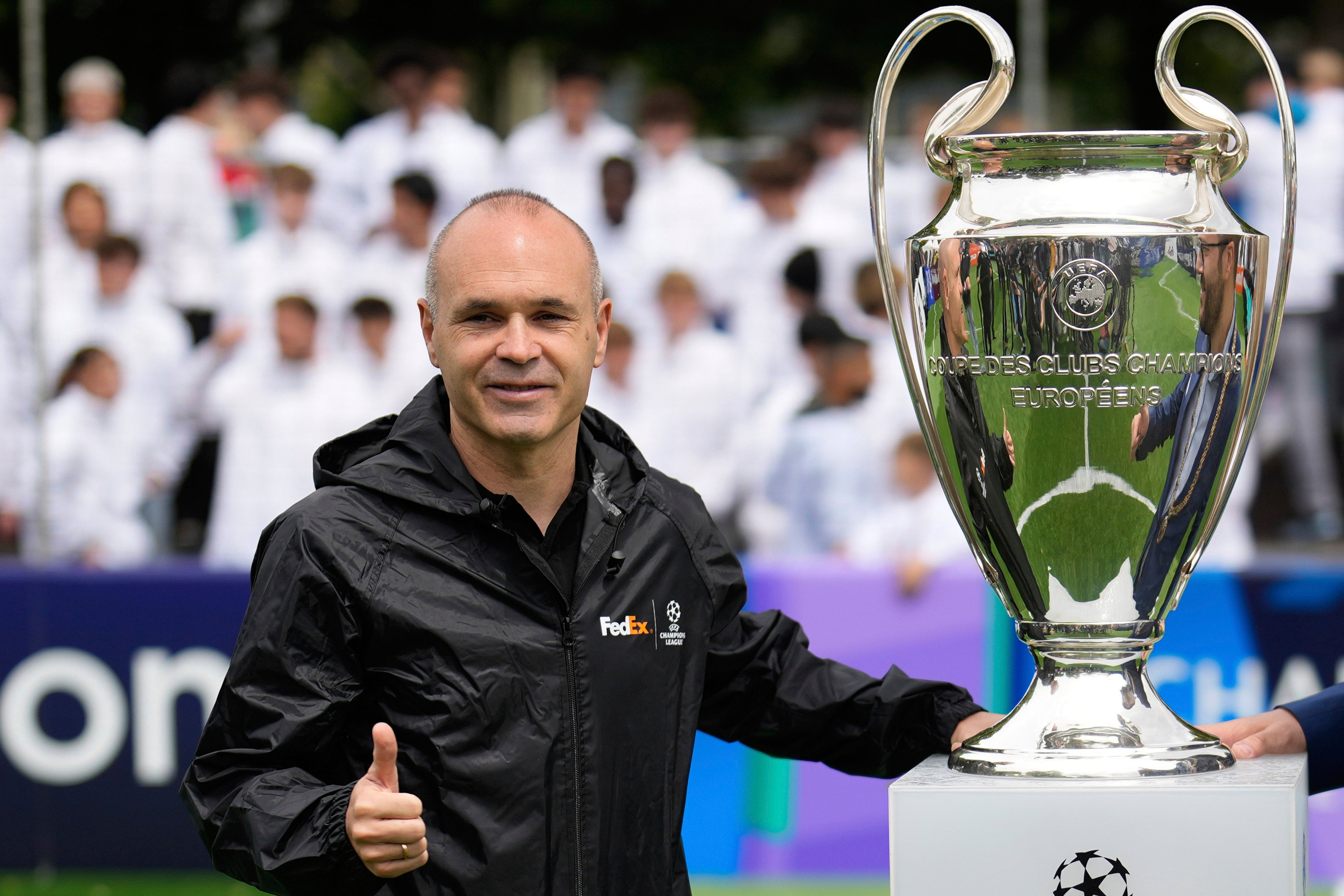 Former soccer player Andres Iniesta poses next to the trophy during the opening of the official UEFA fan festival in Munich, Germany, Thursday, May 29, 2025, ahead of the Champions League final soccer match between Inter and PSG. (AP Photo/Matthias Schrad