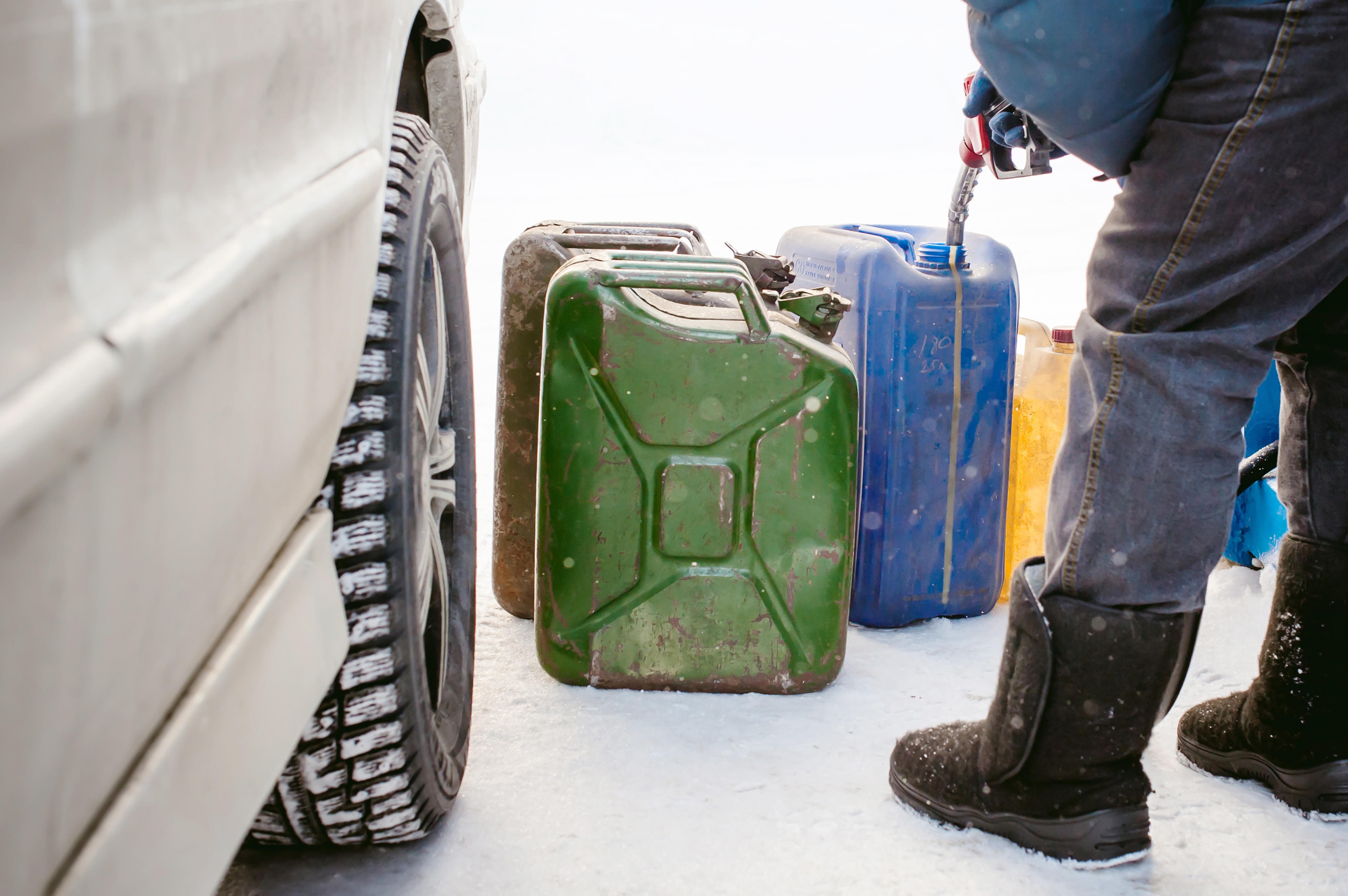 adult man fills a car with petrol at a fuel station in the winter