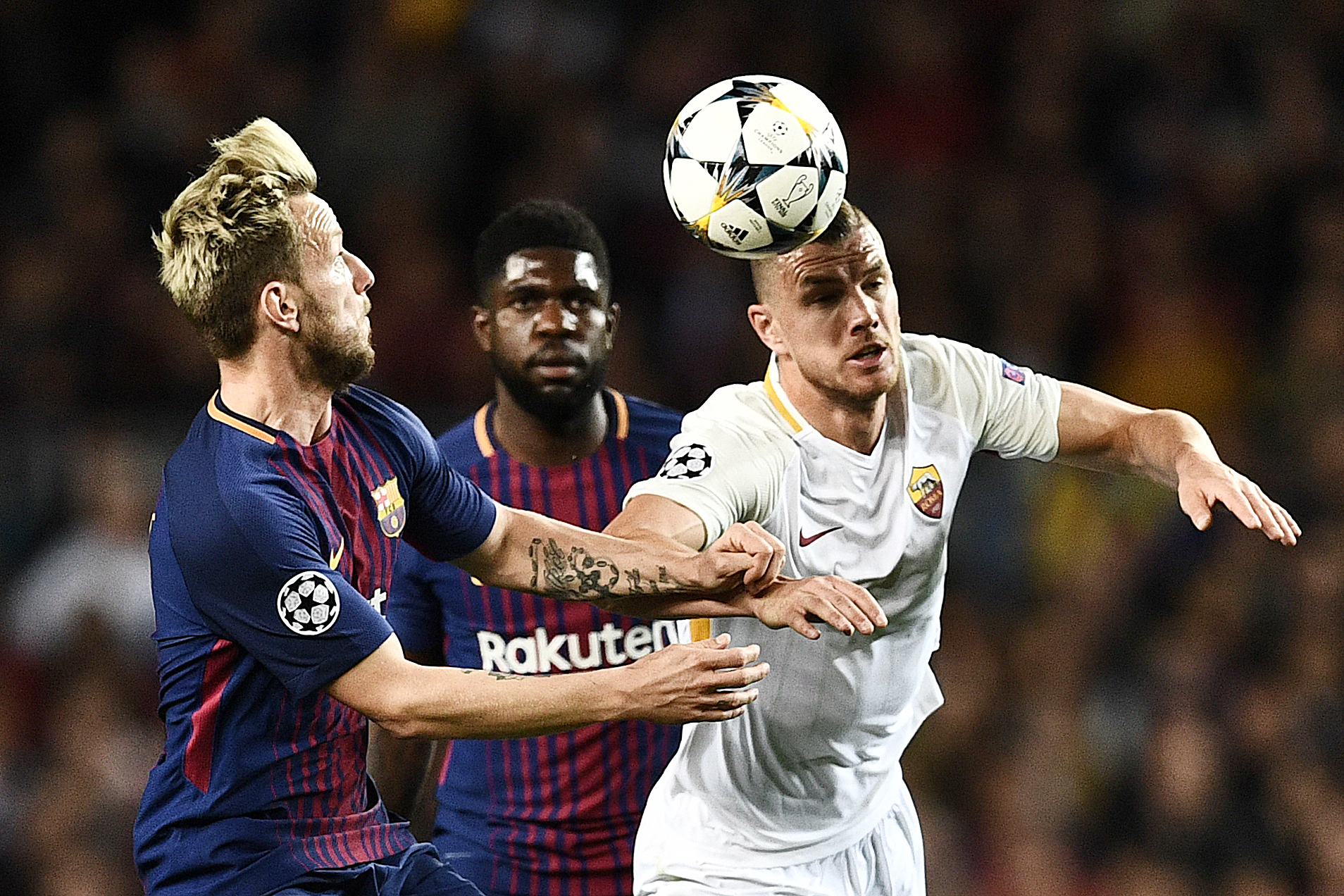 Roma's Bosnian striker Edin Dzeko (R) challenges Barcelona's Croatian midfielder Ivan Rakitic (L) and Barcelona's French defender Samuel Umtiti (C) during the UEFA Champions League quarter-final first leg football match between Barcelona and AS Roma at th