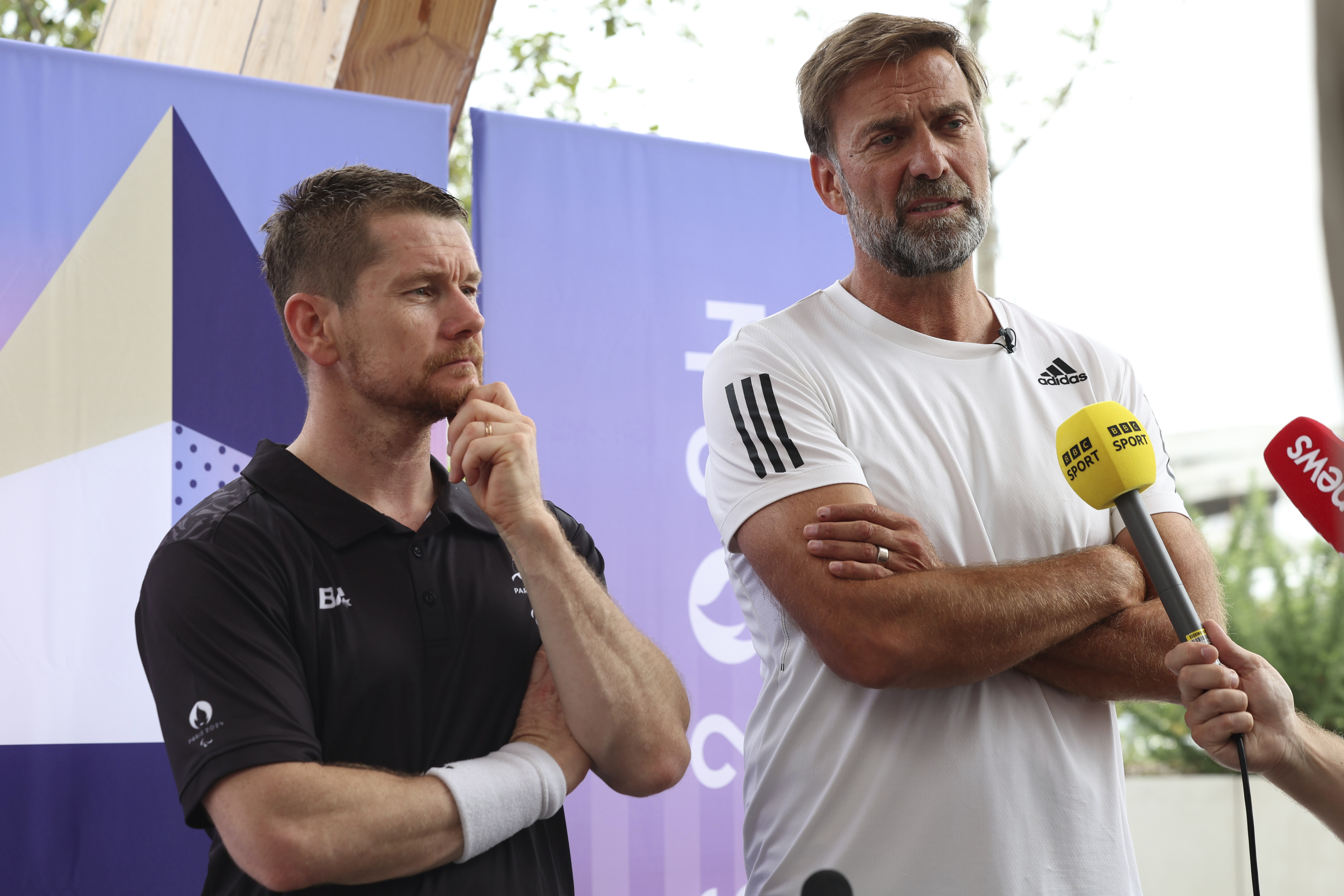 German football manager Jurgen Klopp, right, and para badminton player Wojtek Czyz discuss the results of Czyz's match in Porte La Chapelle Arena during the Paralympic Games on Wednesday, Aug. 28, 2024, in Paris. (AP Photo/Samantha Hurley).
