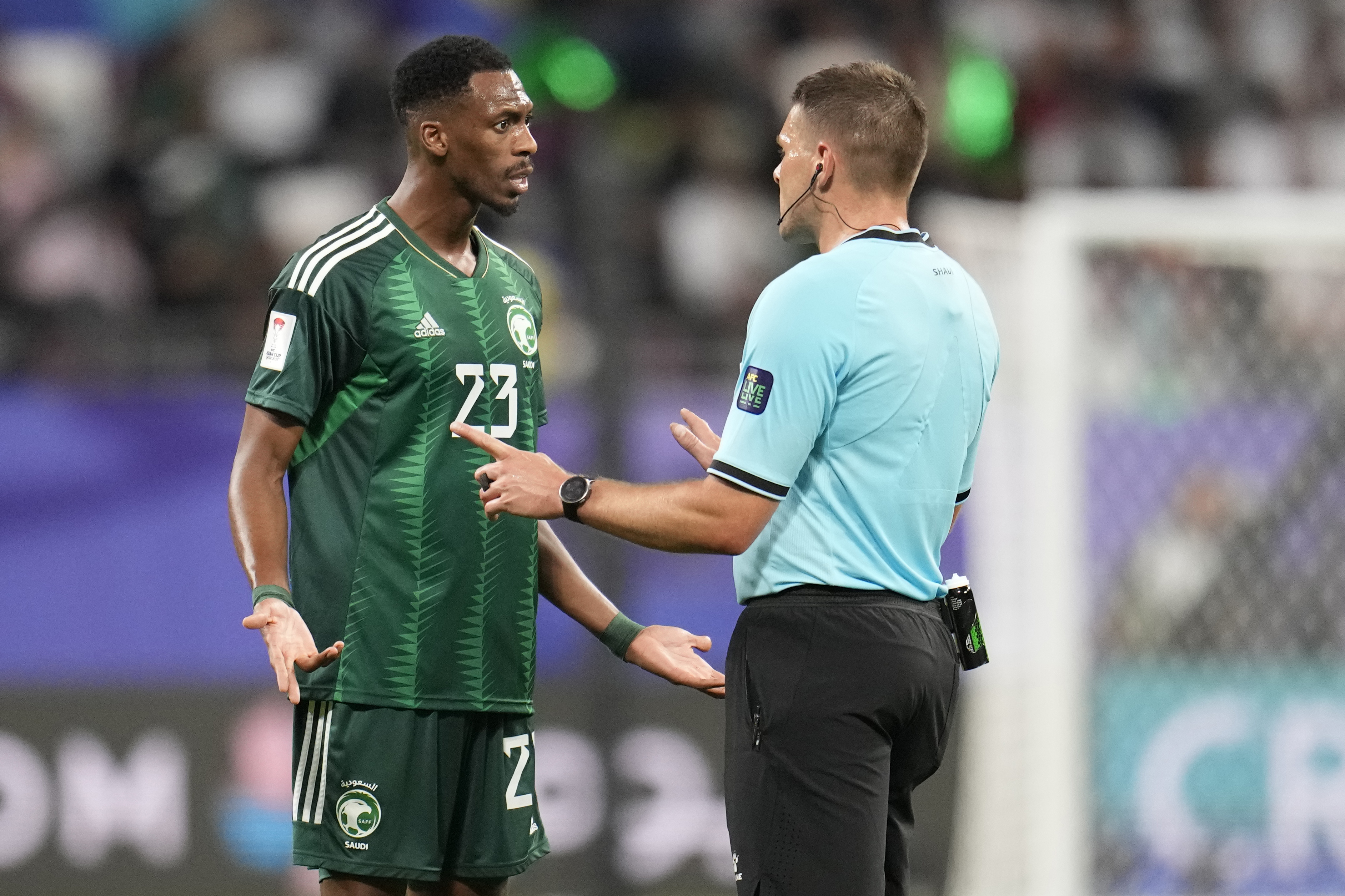Saudi Arabia's Mohamed Kanno, left, reacts against referee's decision Shaun Evans during the Asian Cup Group F soccer match between Saudi Arabia and Oman at Khalifa International Stadium in Doha, Qatar, Tuesday, Jan. 16, 2024. (AP Photo/Aijaz Rahi)