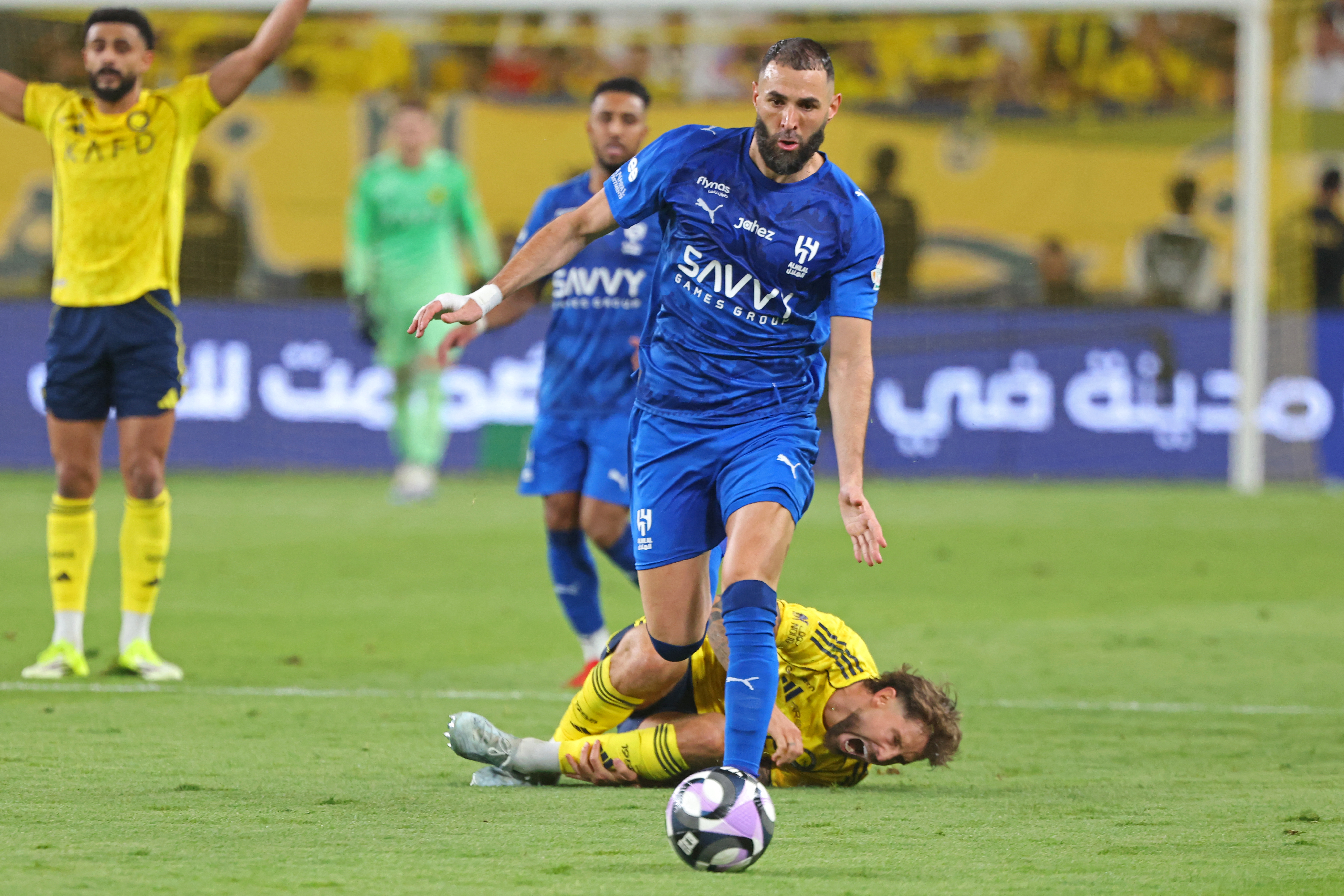 Nassr's Spanish defender #26 Inigo Martinez (down) reacts as Al-Hilal French forward #90 Karim Benzema fights for the ball with during the Saudi Pro League football match between Al-Nassr and Al-Hilal at King Fahd Sports City Stadium in Riyadh on May 12,