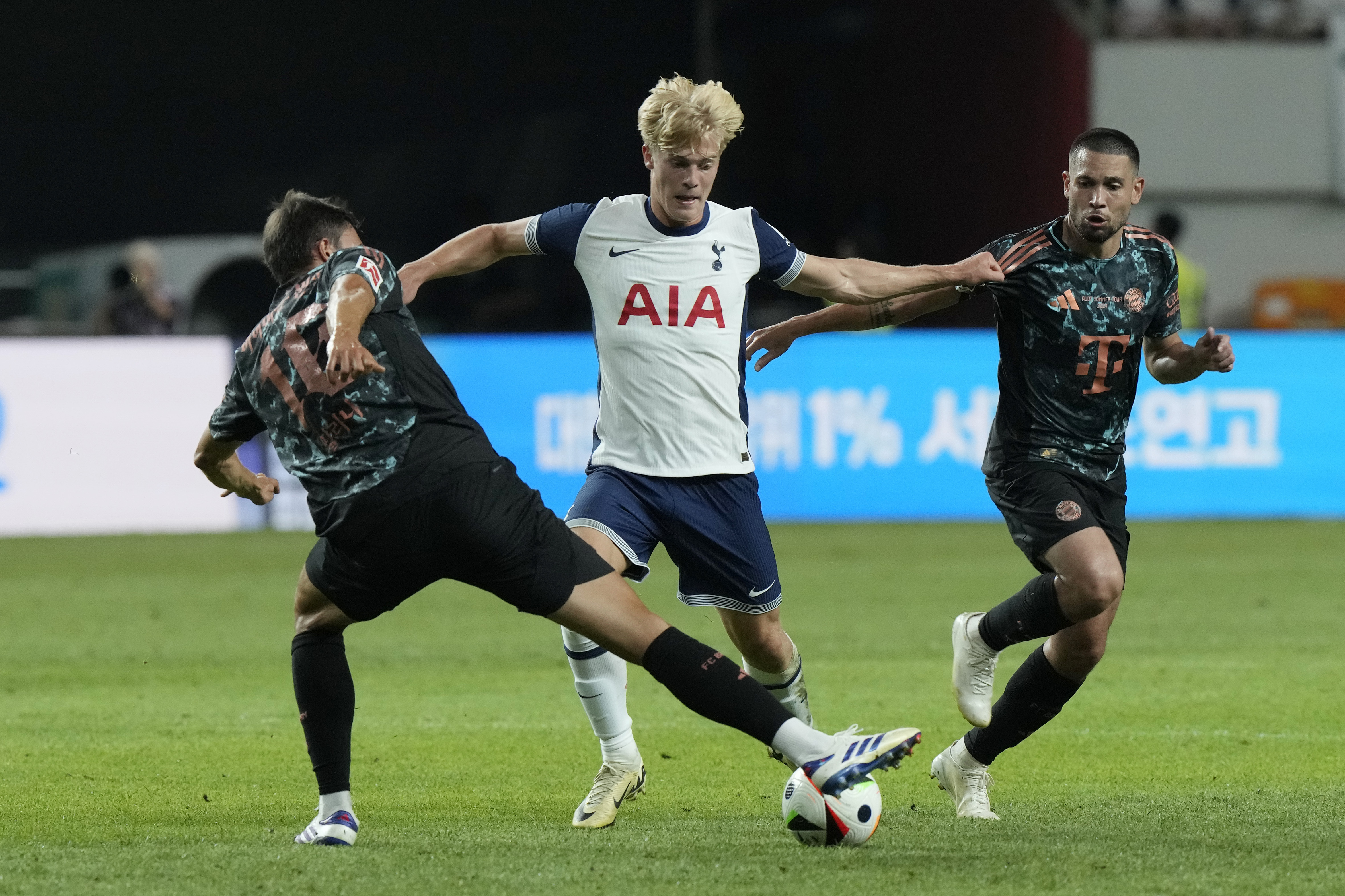 Tottenham Hotspur's Lucas Bergvall, center, fights for the ball with Bayern Munich's Joao Palinha, left, during a preseason soccer match at Seoul World Cup Stadium in Seoul, South Korea, Saturday, Aug. 3, 2024. (AP Photo/Ahn Young-joon)