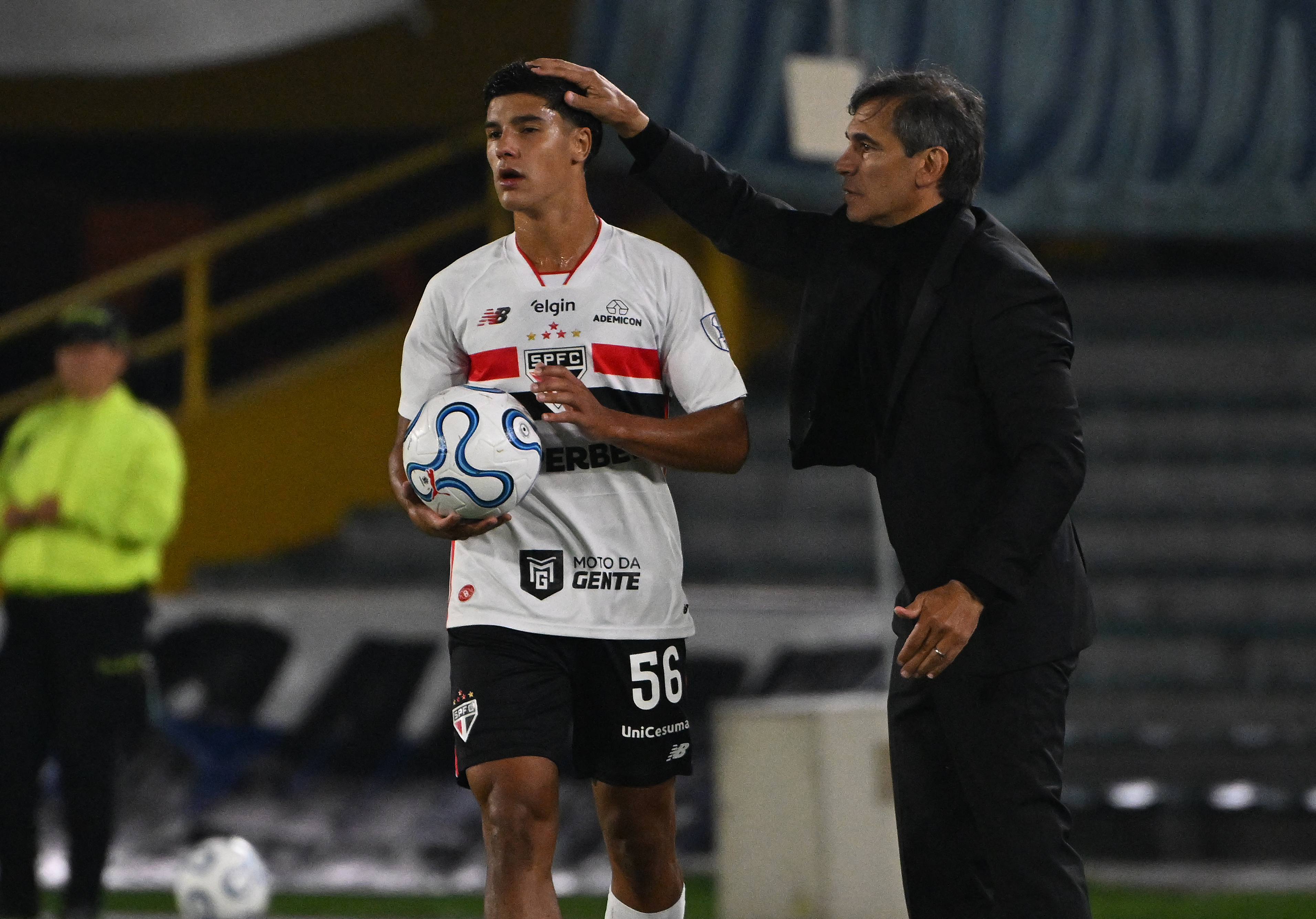 Millonarios' head coach Fabian Bustos (R) touches the head of Sao Paulo's defender #56 Nicolas Bosshardt during the Copa Sudamericana group stage football match between Colombia's Millonarios and Brazil's Sao Paulo at the Nemesio Camacho El Campin stadium