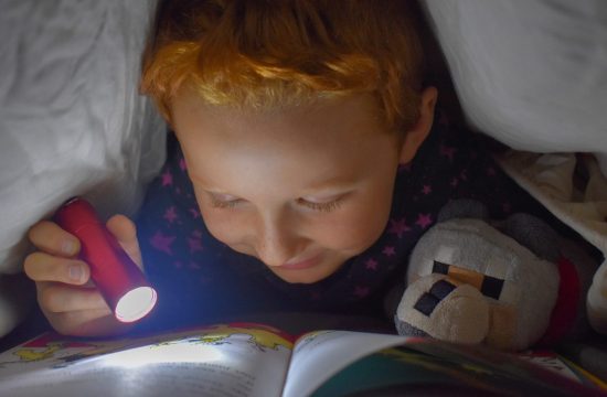 Dijete čita ispod jorgana sa baterijskom lampom